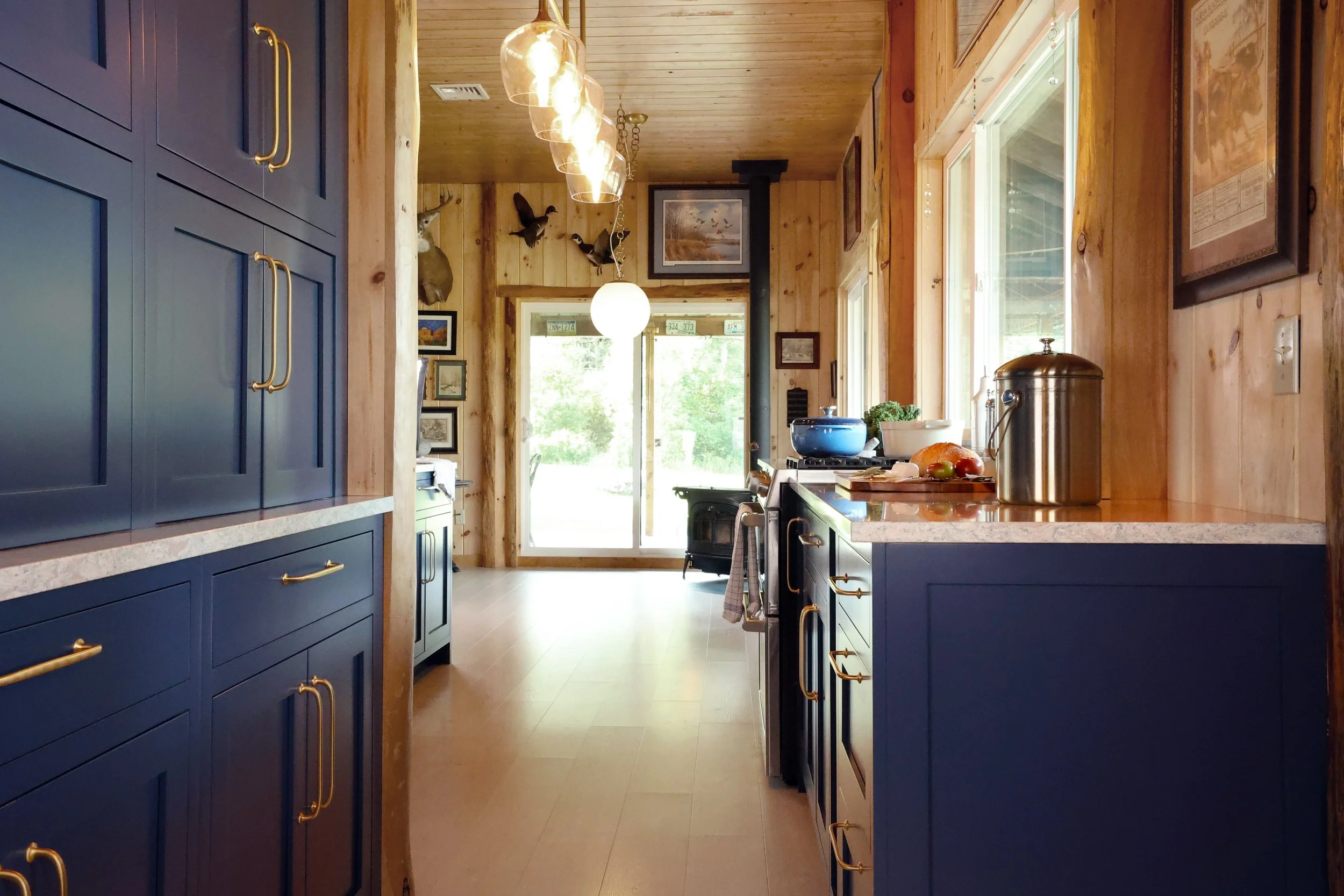 Galley style lodge kitchen with Crown Point Cabinetry and wood walls in a New Hampshire retreat.