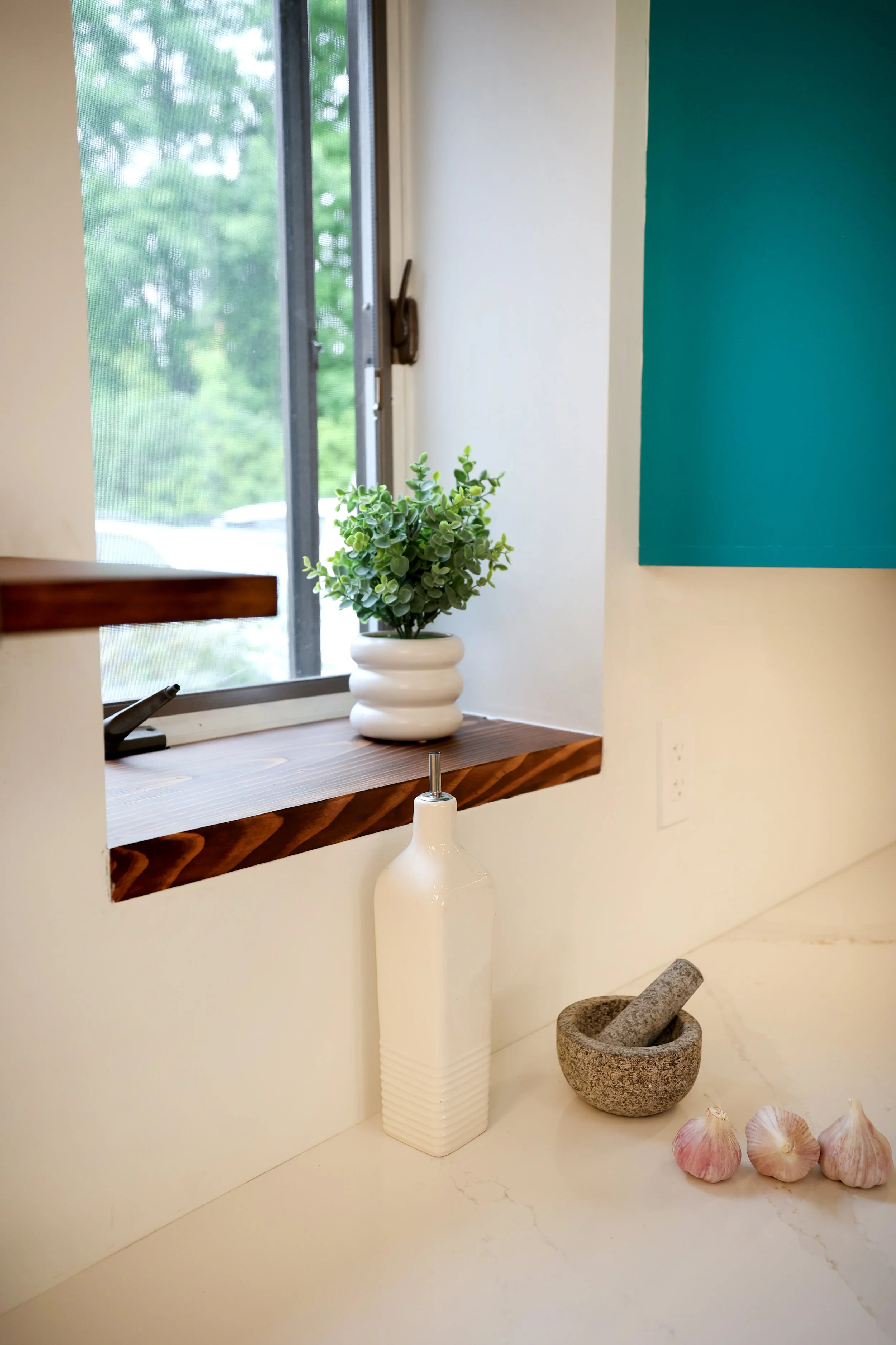 Kitchen window with wood shelf and teal cabinetry in a White River Junction Vermont kitchen renovation.