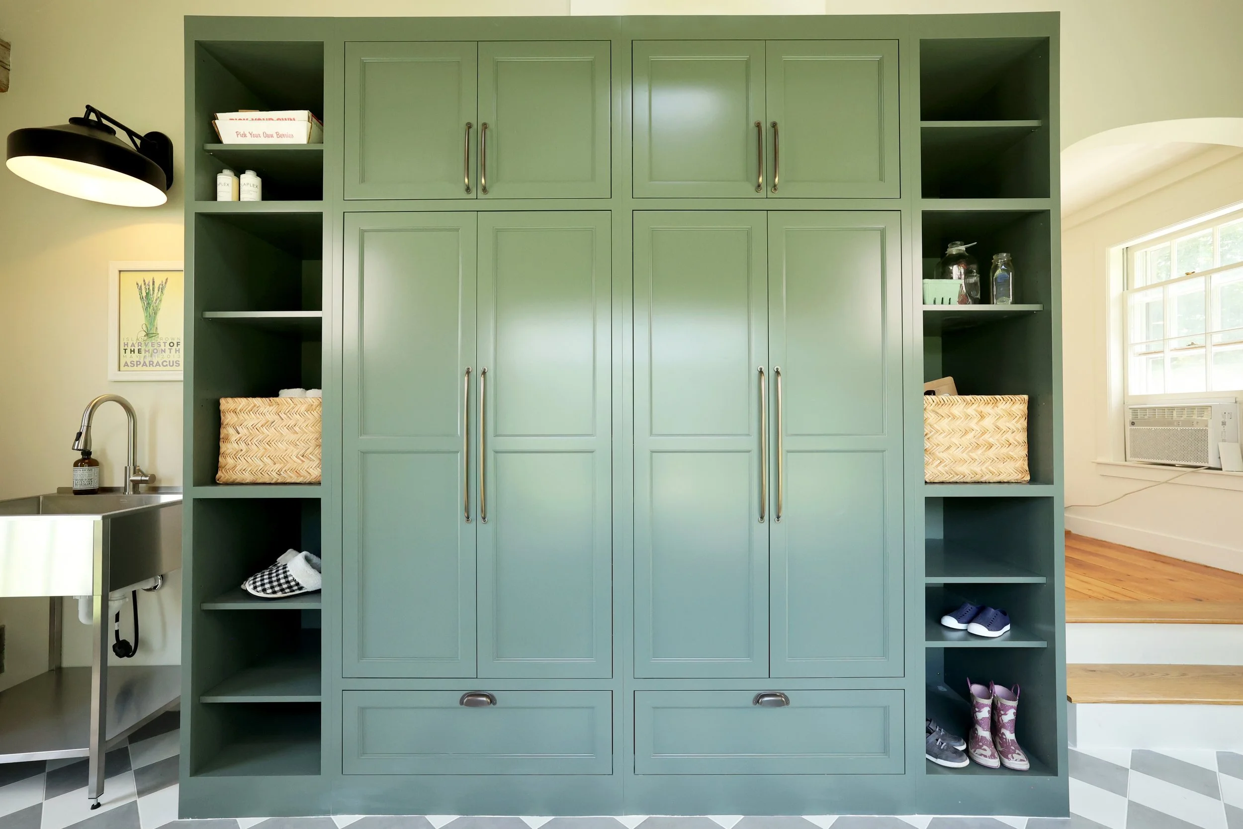 Full wall of custom green mudroom cabinetry by Crown Point Cabinetry in a Thetford Vermont farmhouse.