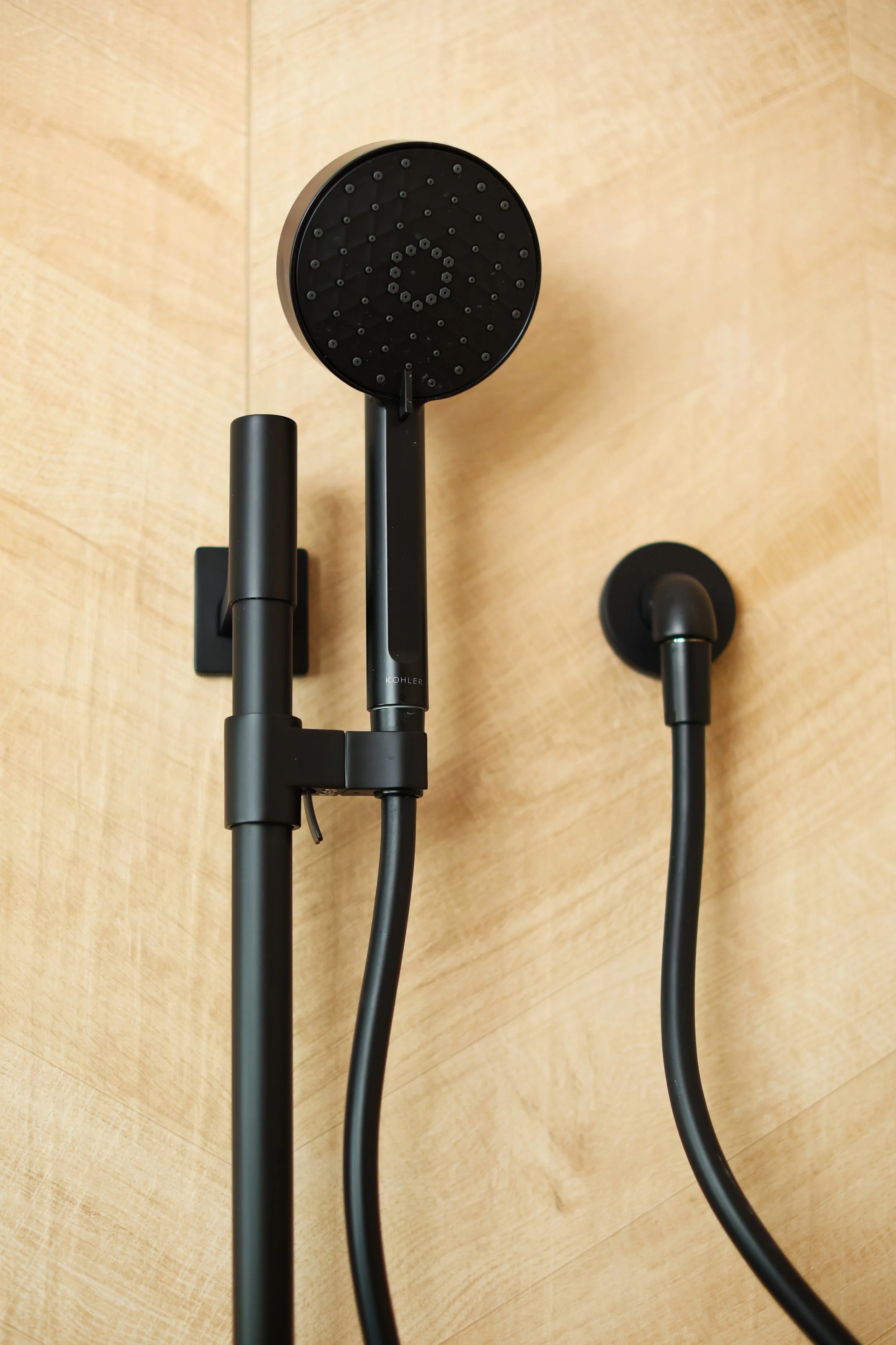 Matte black Kohler shower fixtures installed on chevron wood-look tile in a Burke Vermont ski home.
