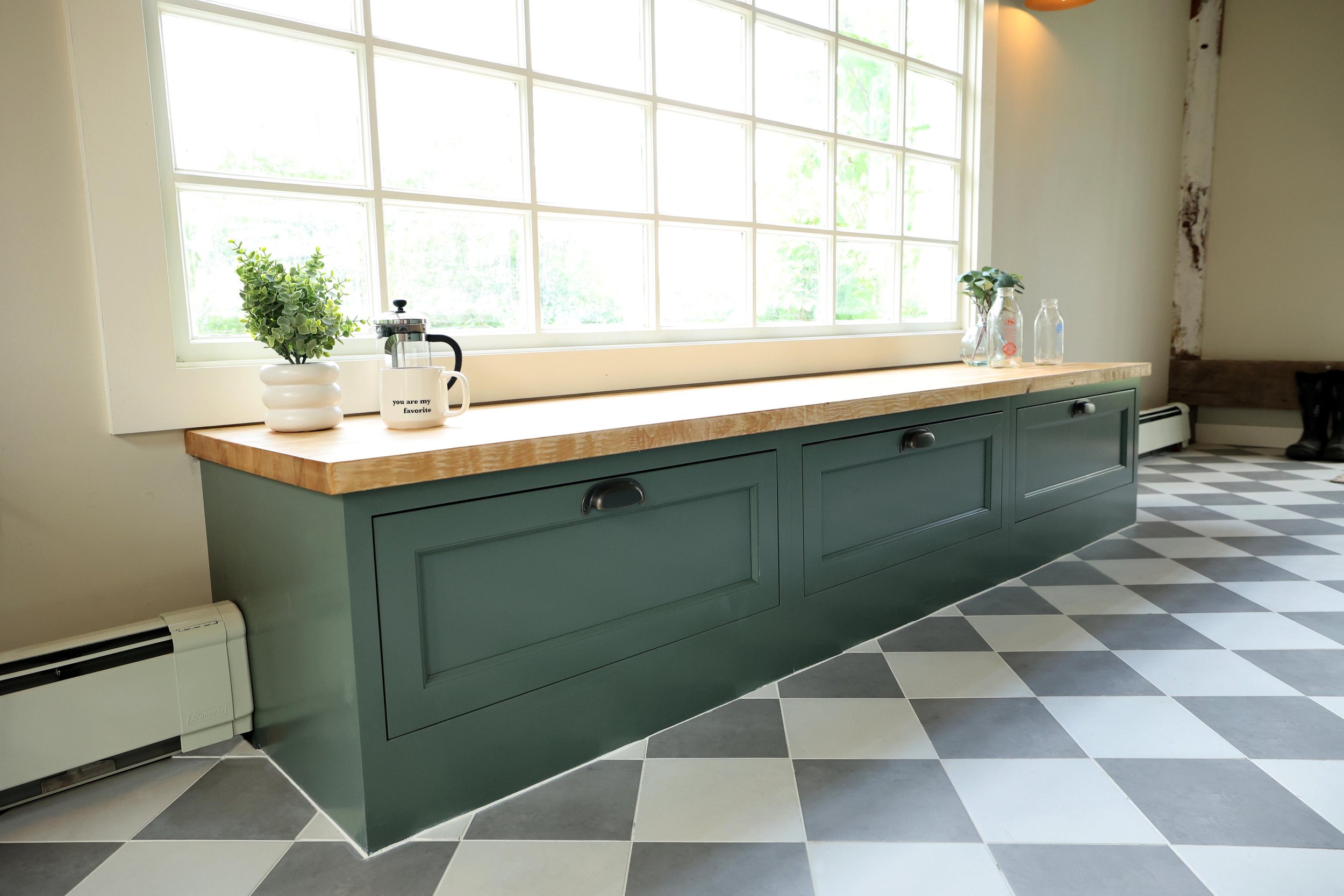 Long mudroom bench with storage beneath a large window in an Upper Valley farmhouse.
