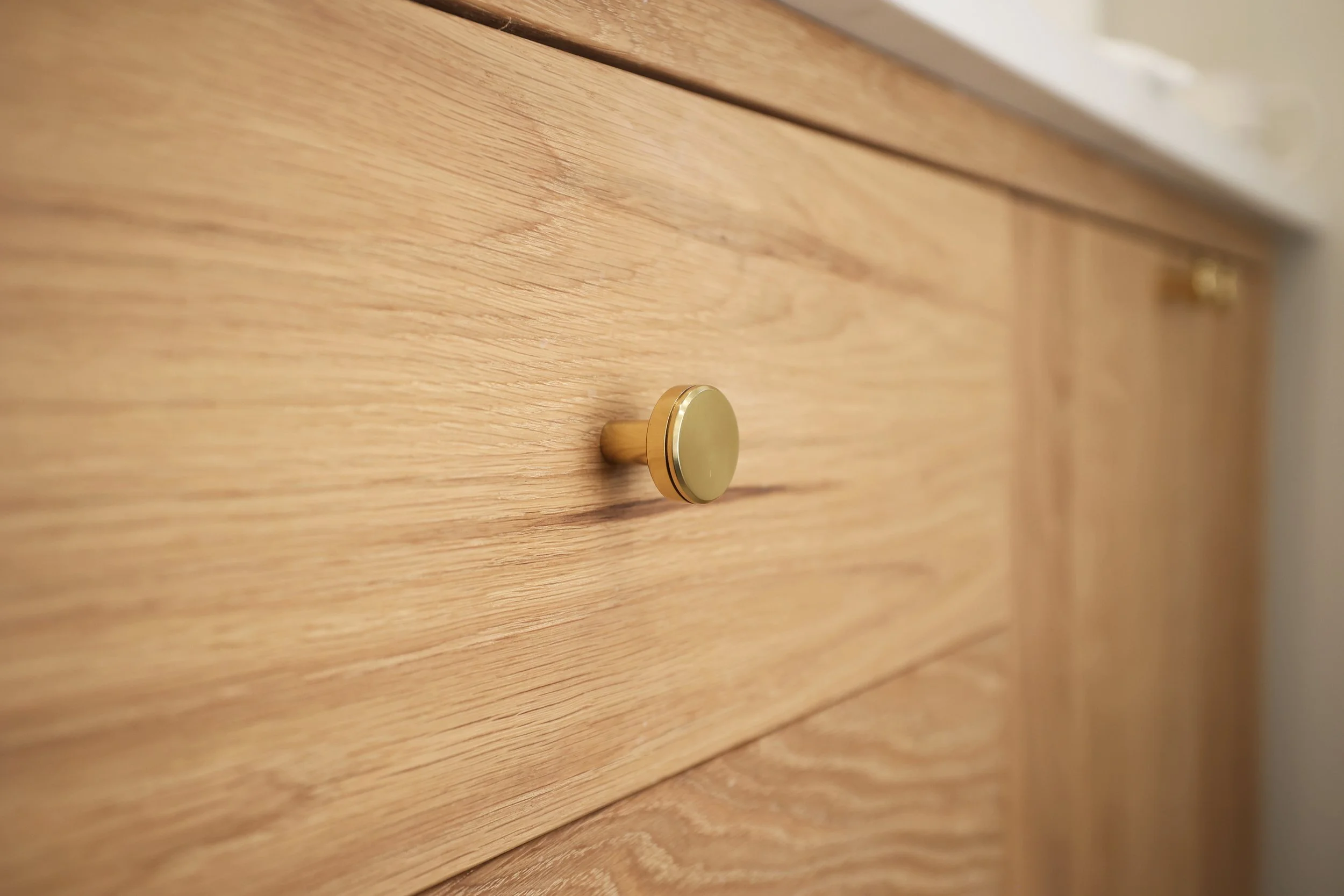 Natural oak vanity drawer with round brass hardware in a warm, organic modern primary bath.