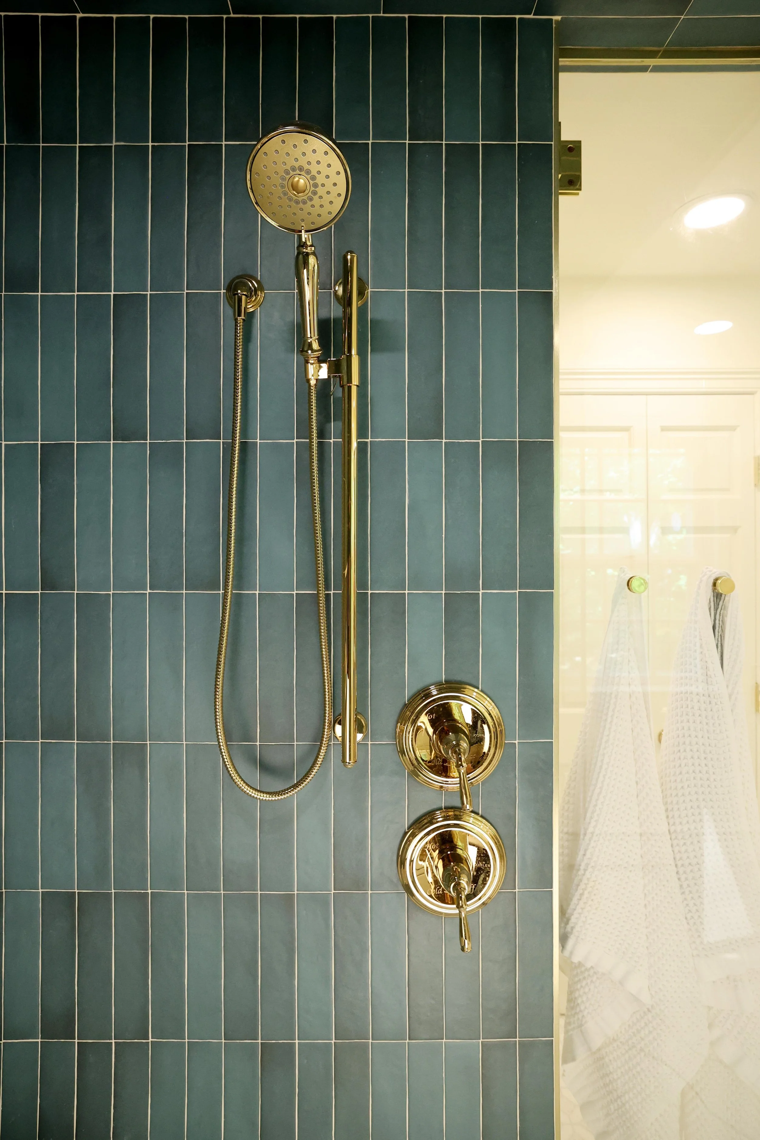 Close-up of brass shower fixture against deep blue tile in primary bathroom