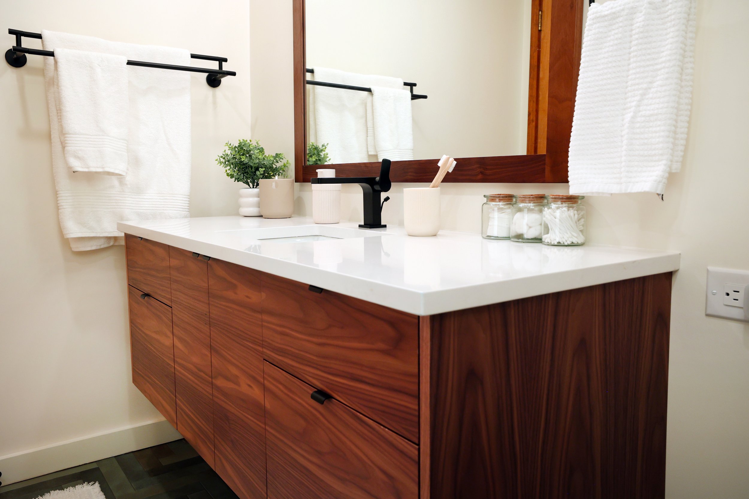 White countertop and matte black faucet paired with walnut vanity in a Hanover NH midcentury bathroom.