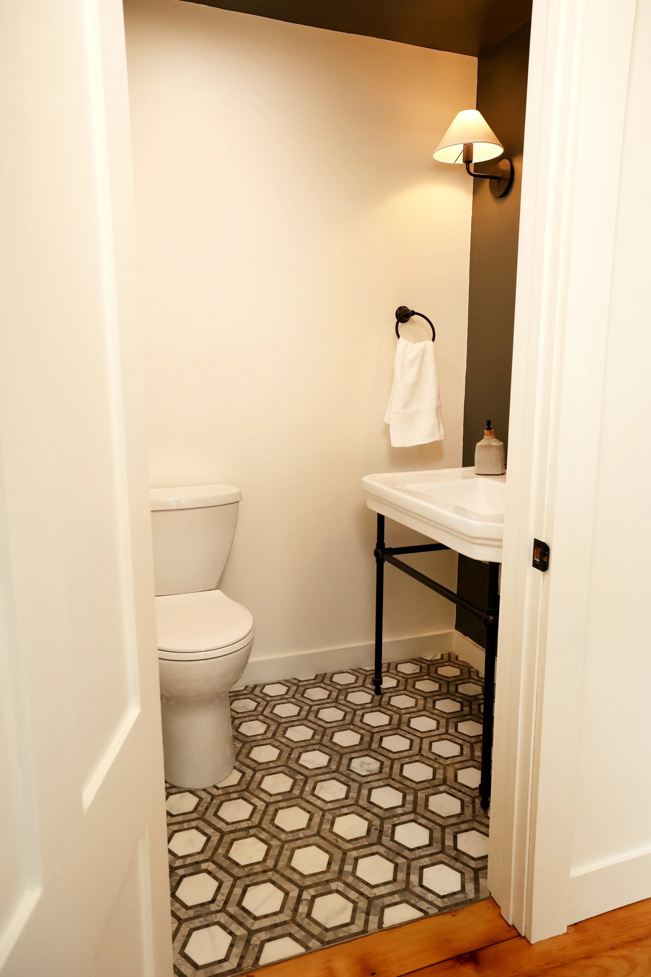 Small powder room with marble mosaic floor and console sink in a Thetford Vermont home.