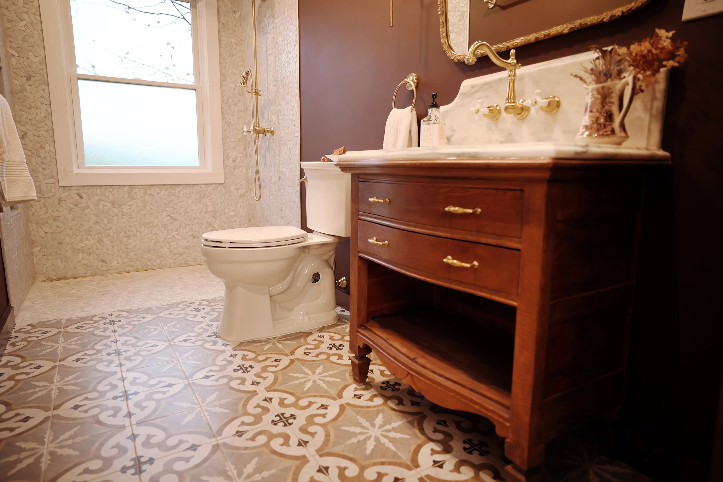 Patterned floor tile and antique dresser vanity in a historic bathroom renovation.