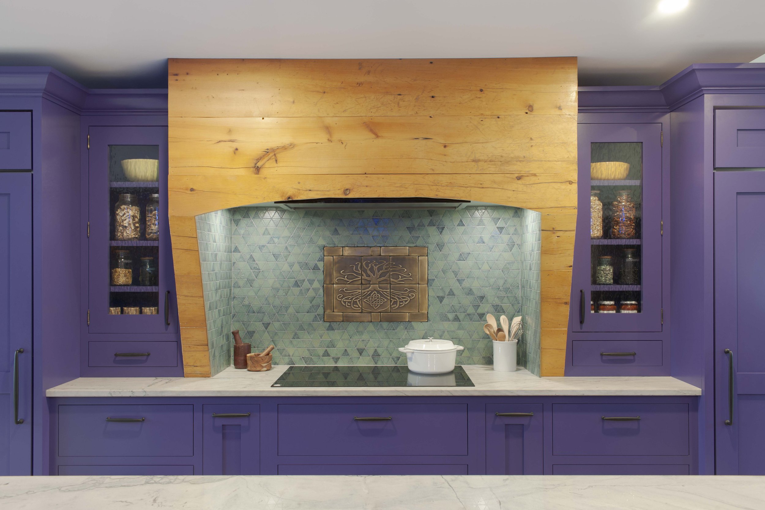 Range alcove with lava stone mosaic tile backsplash framed with reclaimed wood from the original kitchen flooring.