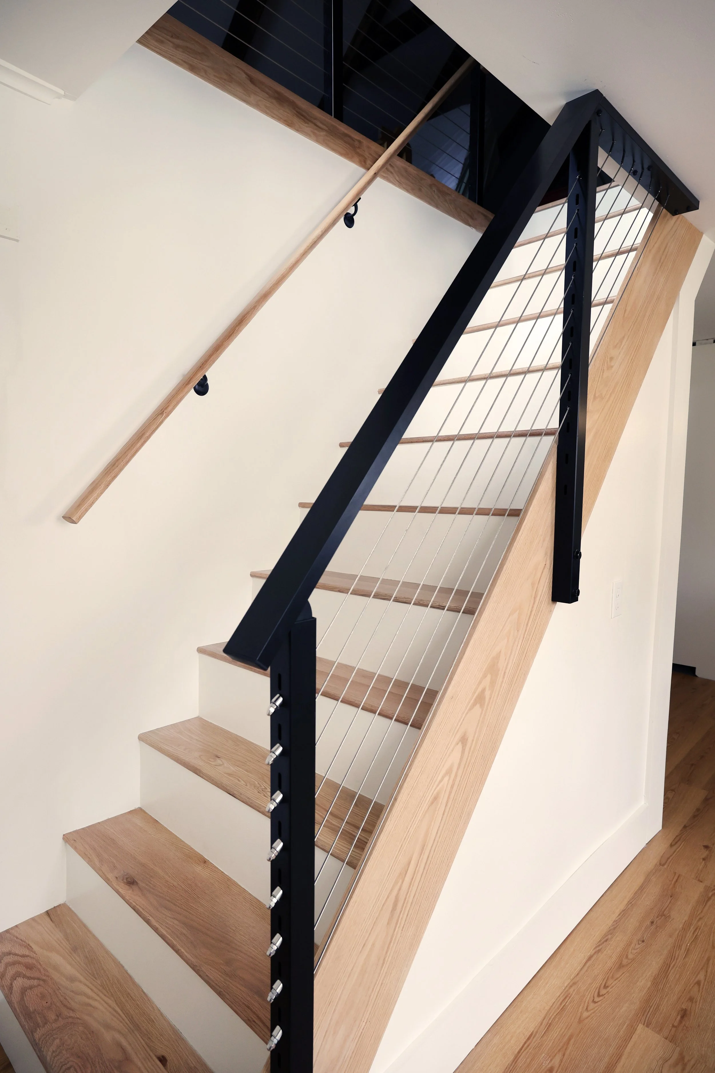Black stair railing detail integrated beside a renovated historic farmhouse kitchen in Bethlehem NH.