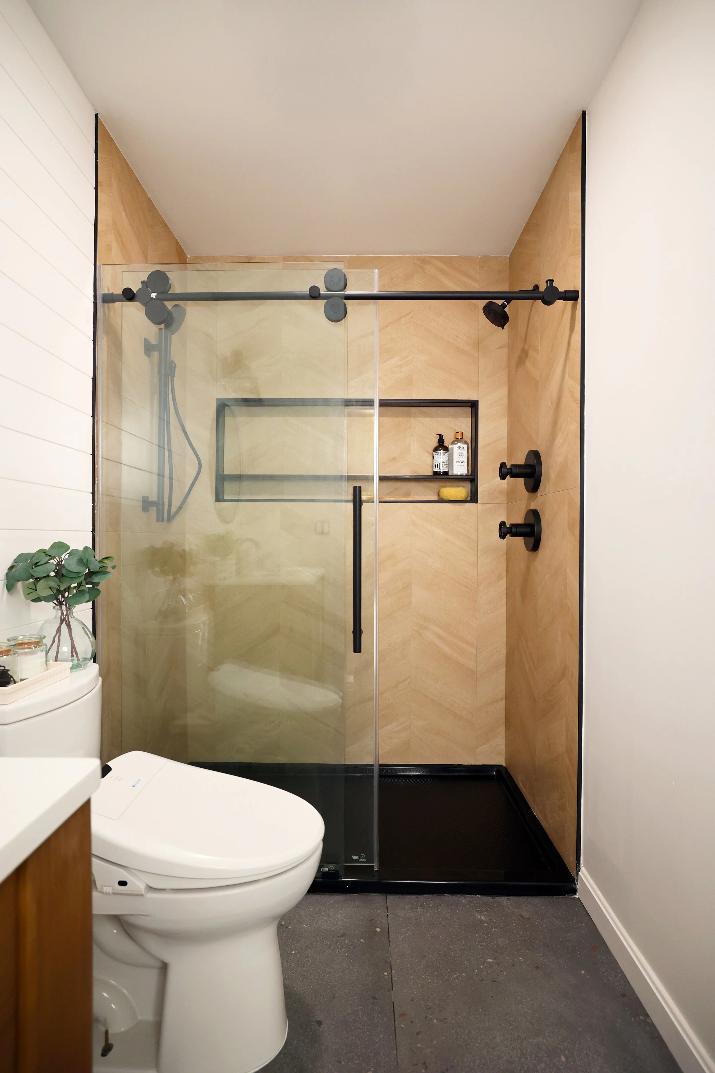 Glass enclosed shower with wood-look chevron tile in a Burke Vermont ski house bathroom.