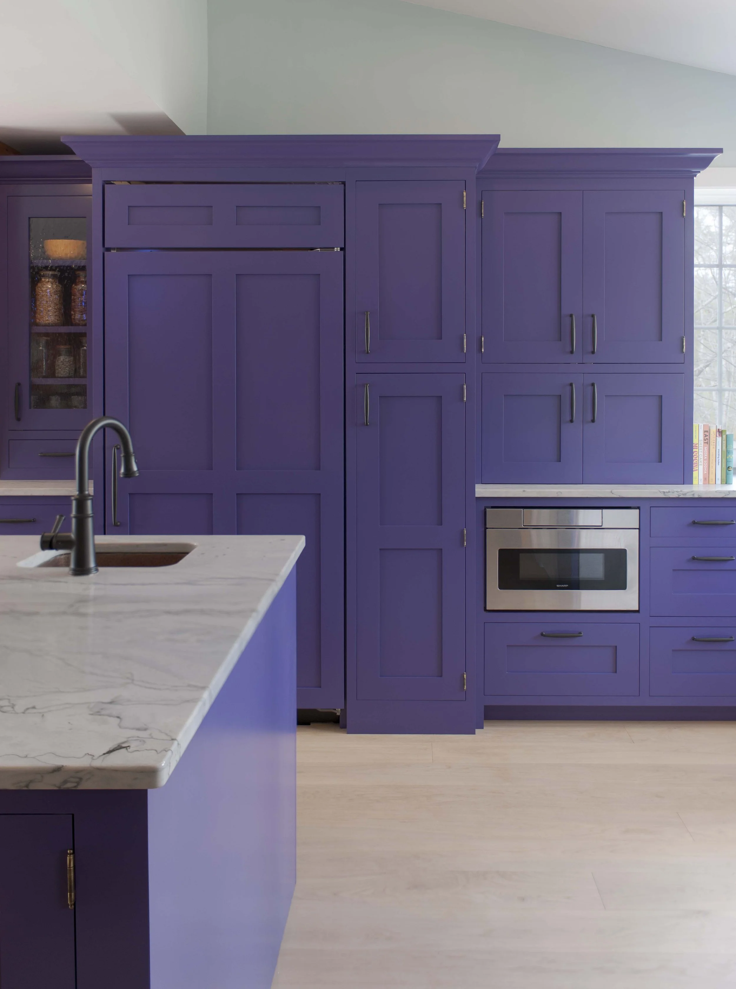  Kitchen renovation featuring custom purple cabinetry by crown point cabinetry in claremont new hampshire, marble countertops, and integrated appliances designed for a modern New England home. 