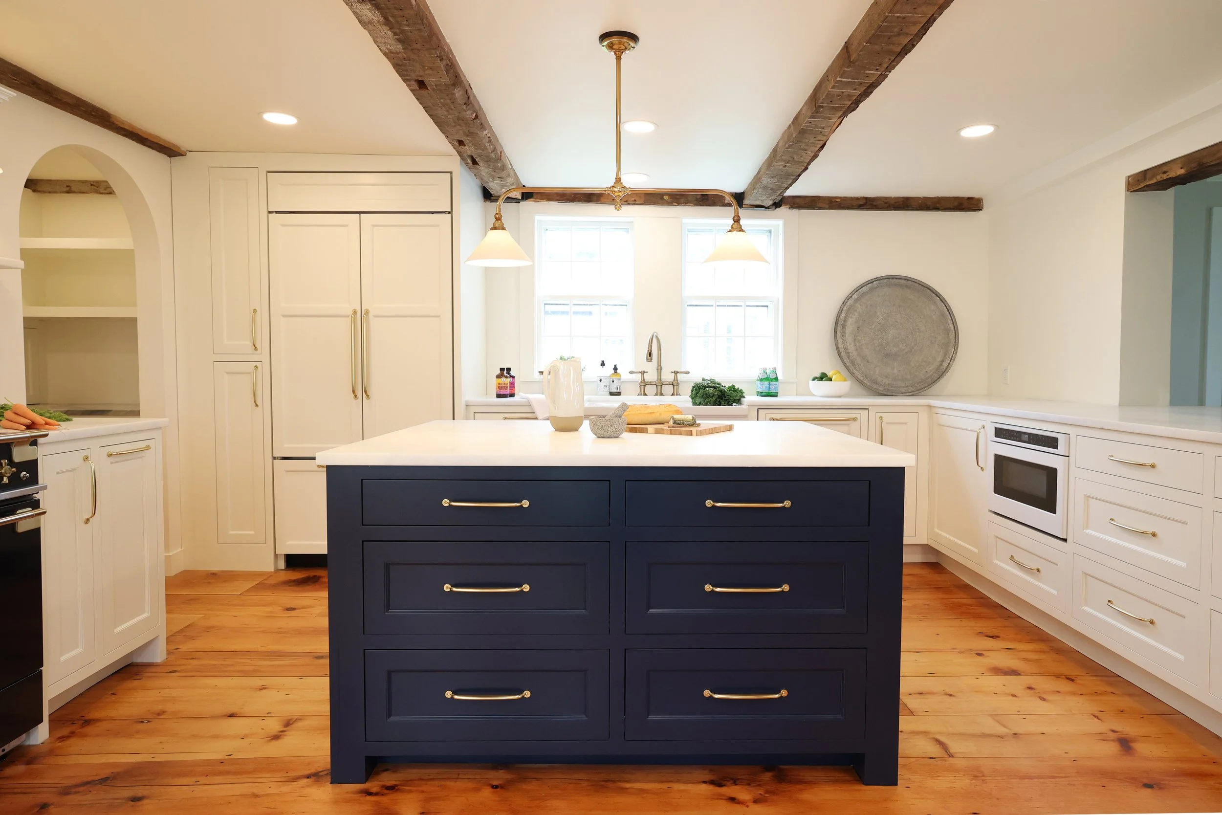 Vermont kitchen renovation featuring a navy island, cream shaker cabinets, and exposed wood beams.