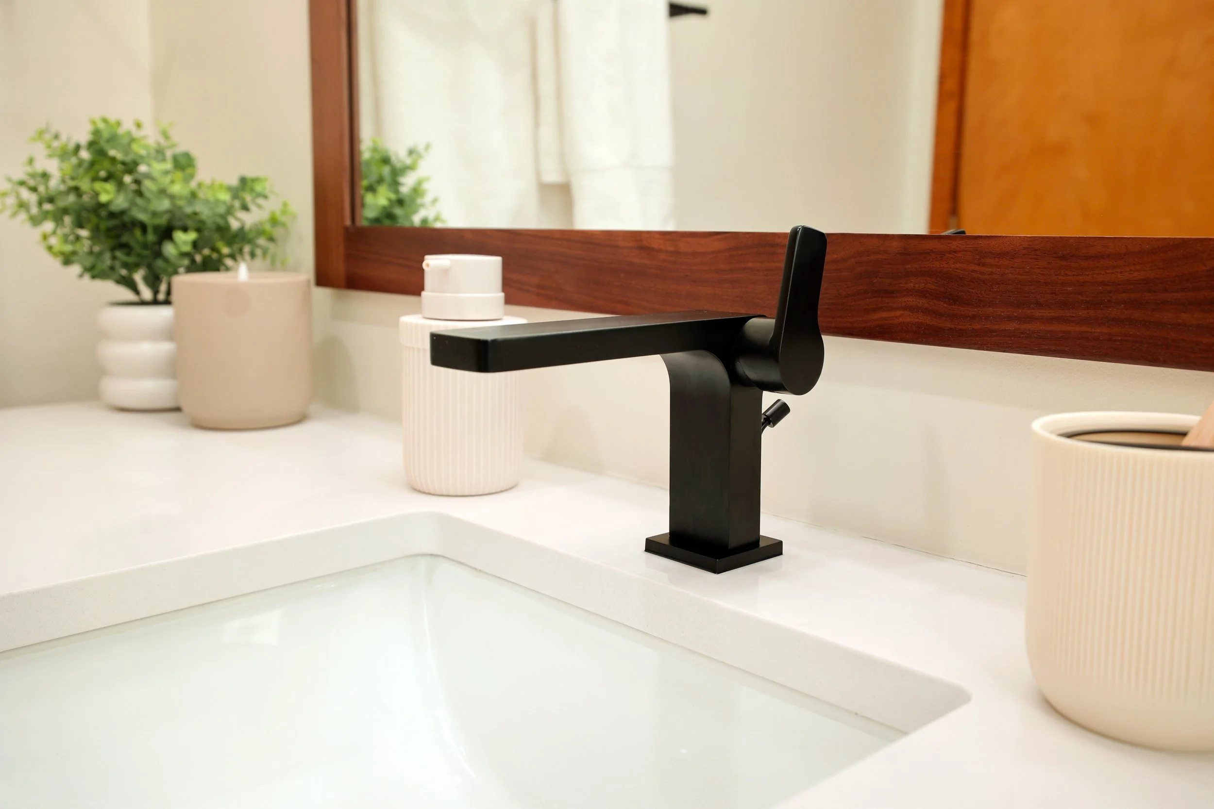 Matte black faucet on white countertop with walnut vanity in a midcentury bathroom in Hanover NH.