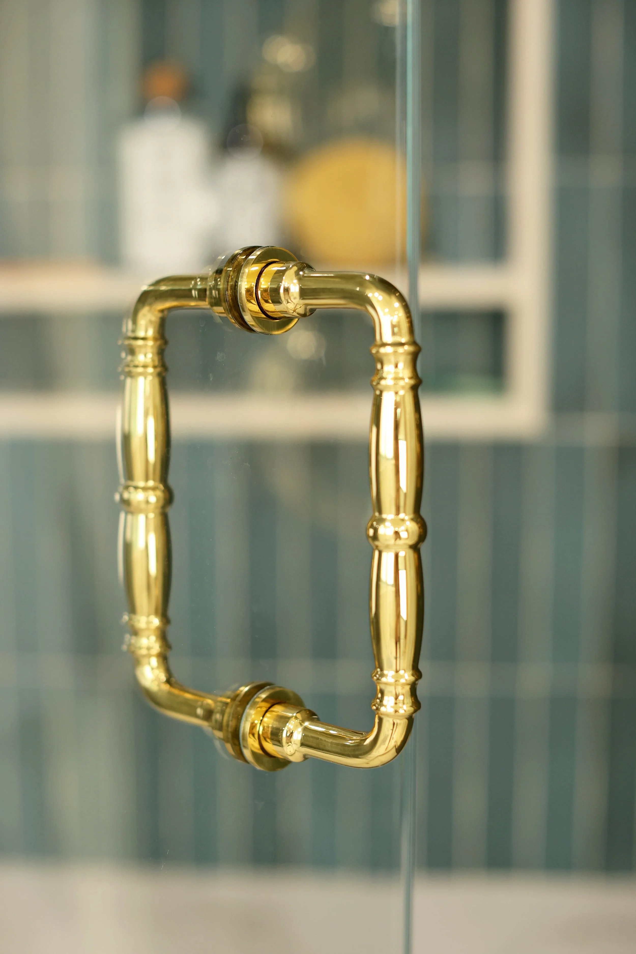 Brass shower door handle on clear glass enclosure in Hanover NH primary bathroom