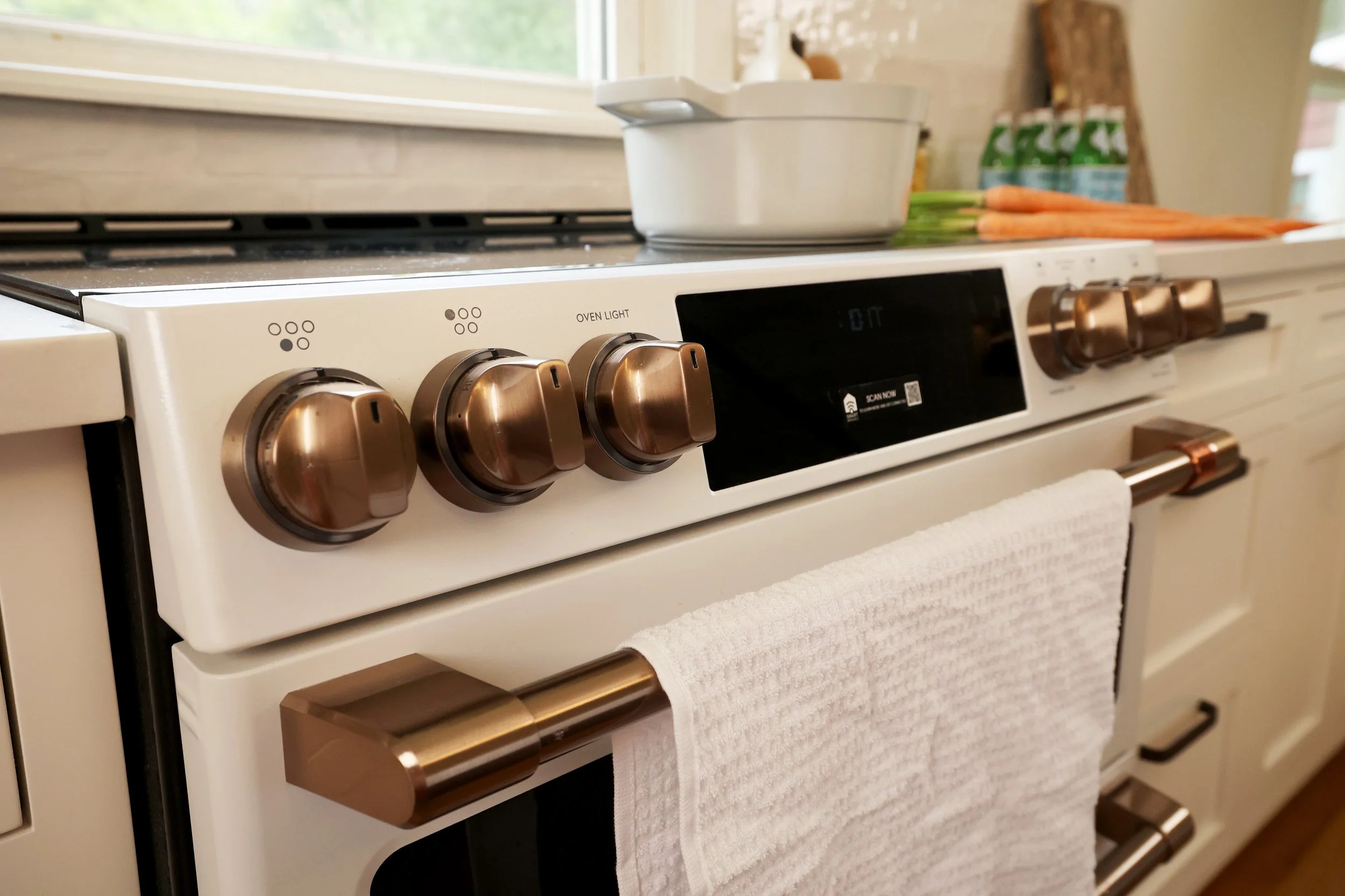 GE Café induction range with warm metal knobs set within cream cabinetry in a historic Bethlehem NH farmhouse kitchen.