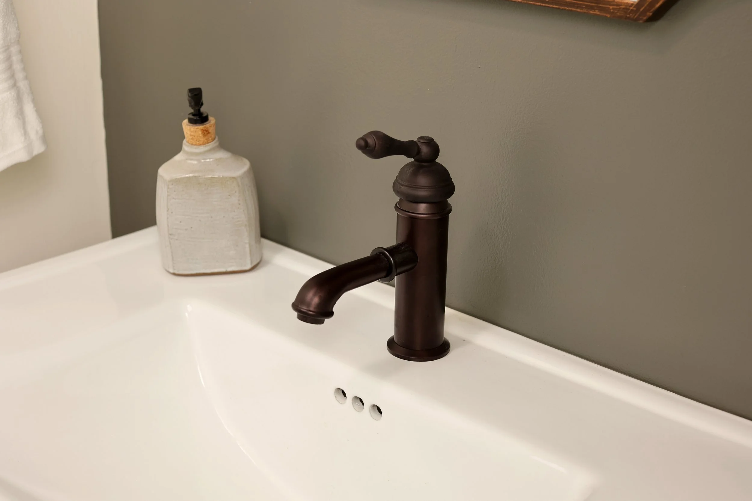 Console sink with oil-rubbed bronze faucet and mirror in a classic powder room design.