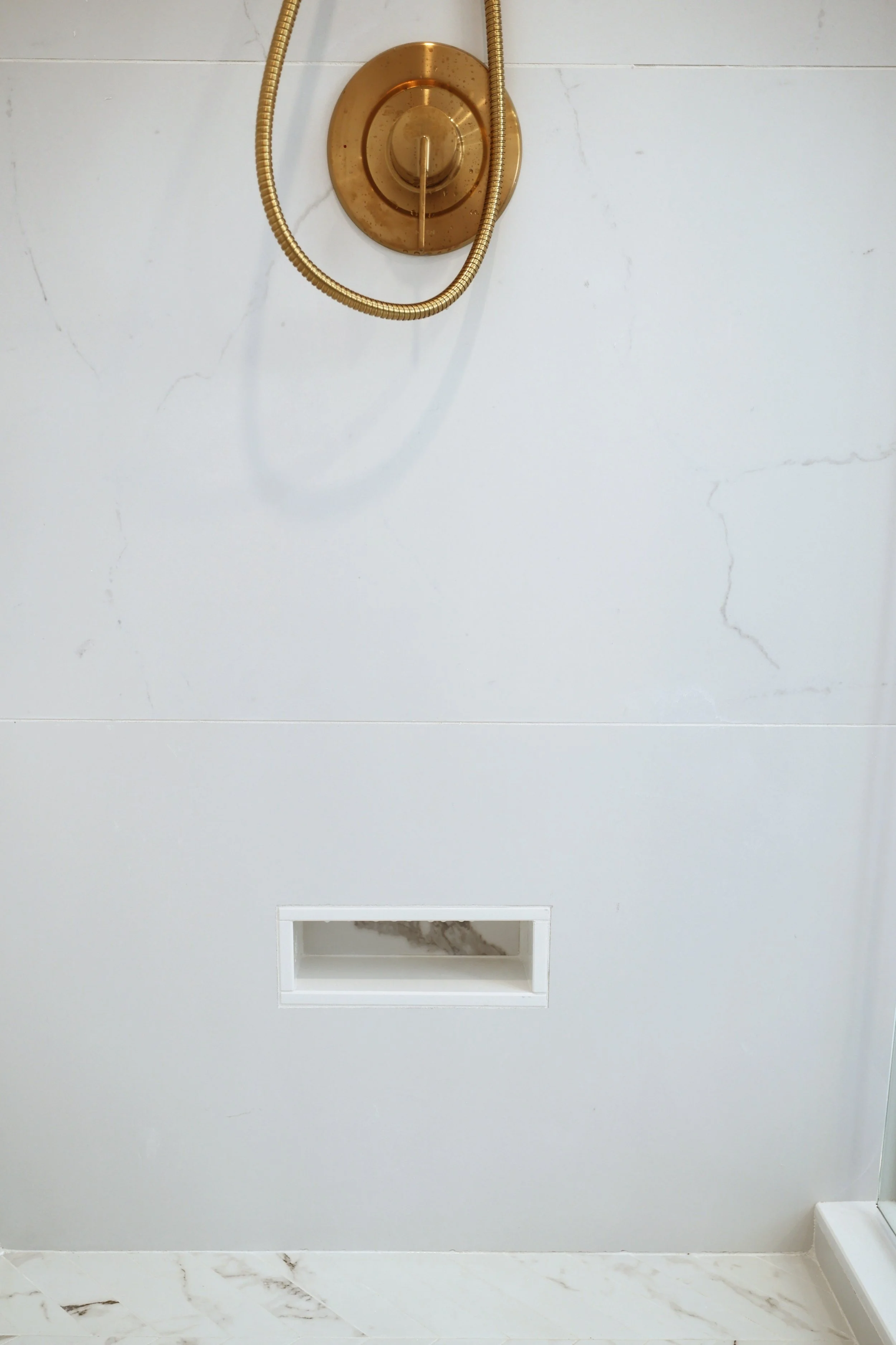 Built-in marble shower shaving ledge for leg shaving in a Lebanon NH primary bathroom renovation.