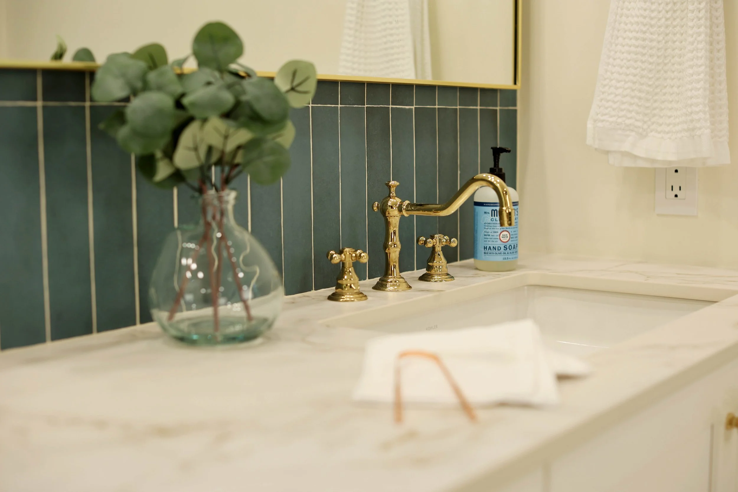 Polished brass faucet on cream vanity with marble countertop in Hanover NH primary bathroom