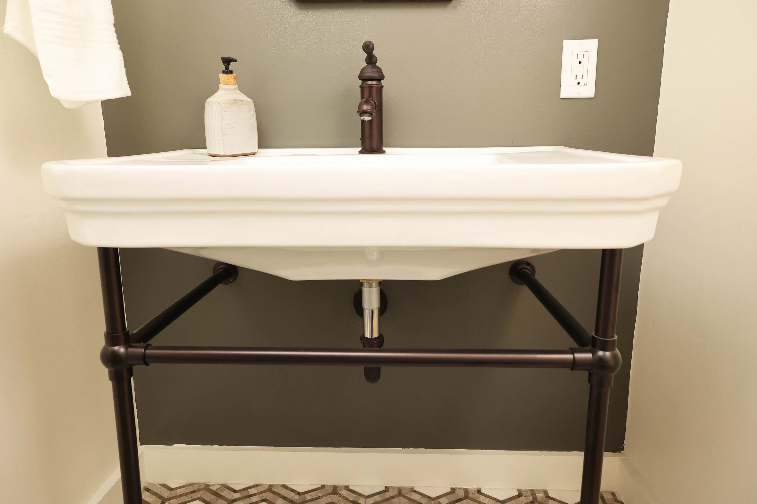 Wall-mounted console sink with oil-rubbed bronze faucet in a classic Upper Valley powder room.