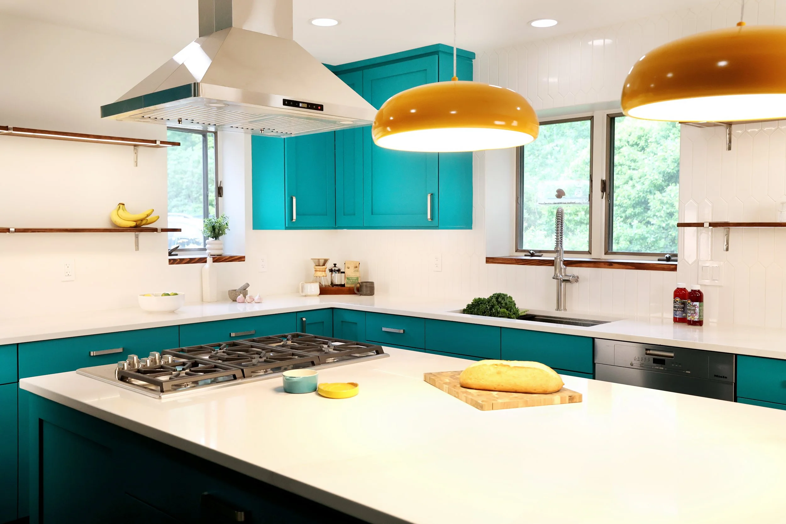 Teal kitchen cabinetry with orange pendant lighting in a midcentury kitchen in White River Junction VT.