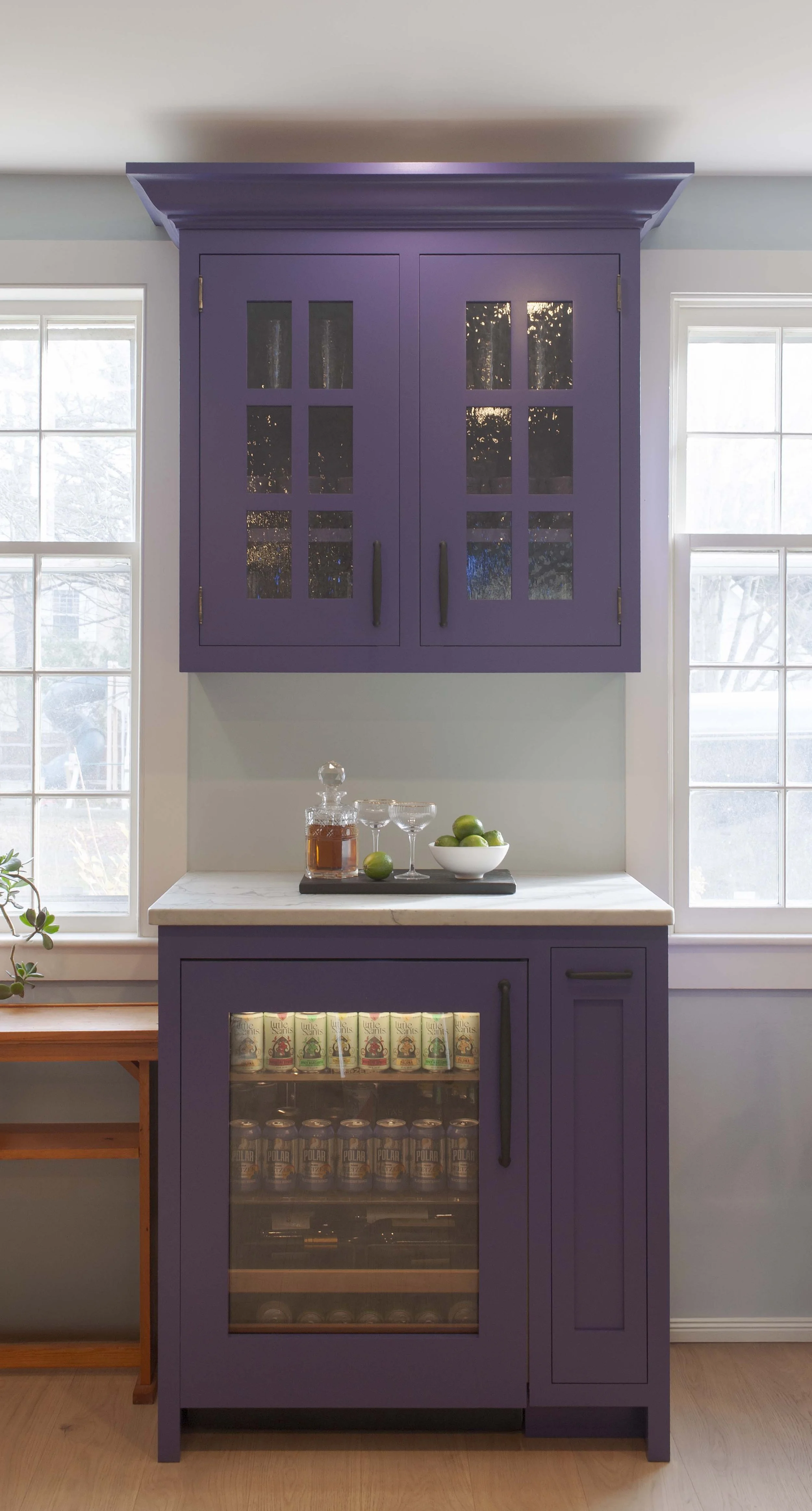 Glass-front Crown Point Cabinetry painted Sherwin Williams Fully Purple with a panel ready SubZero beverage refrigerator in a Norwich Vermont kitchen.