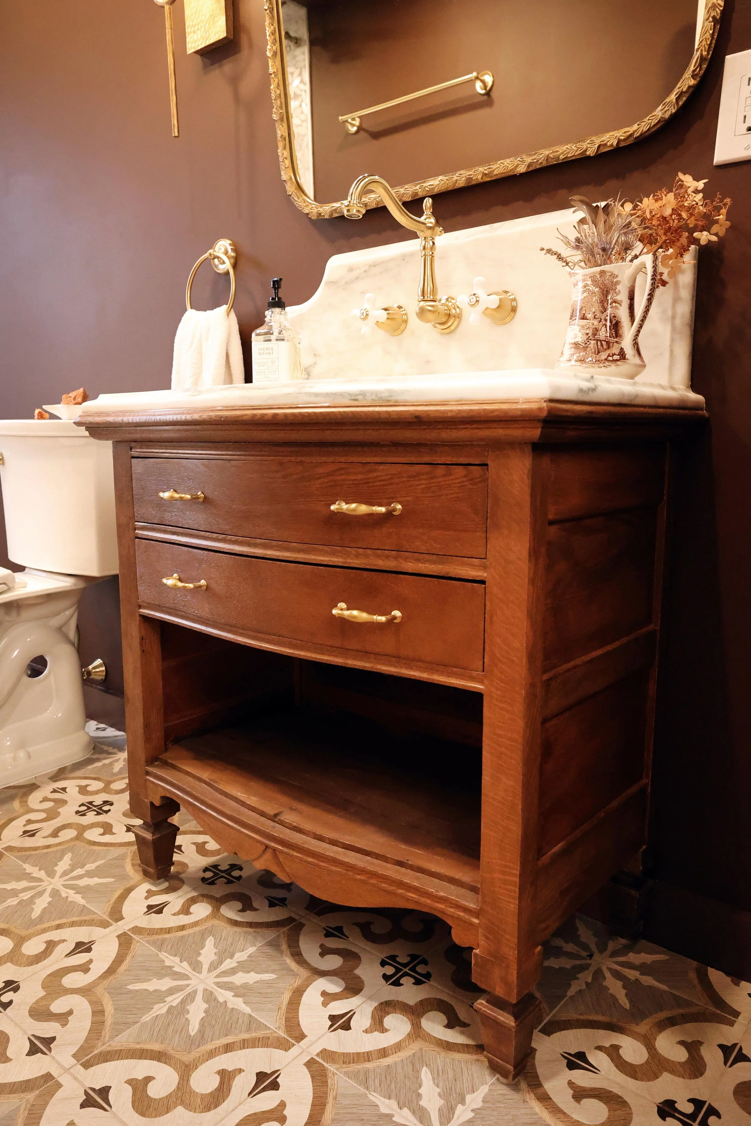 Converted antique dresser vanity with marble countertop and brass drawer pulls.