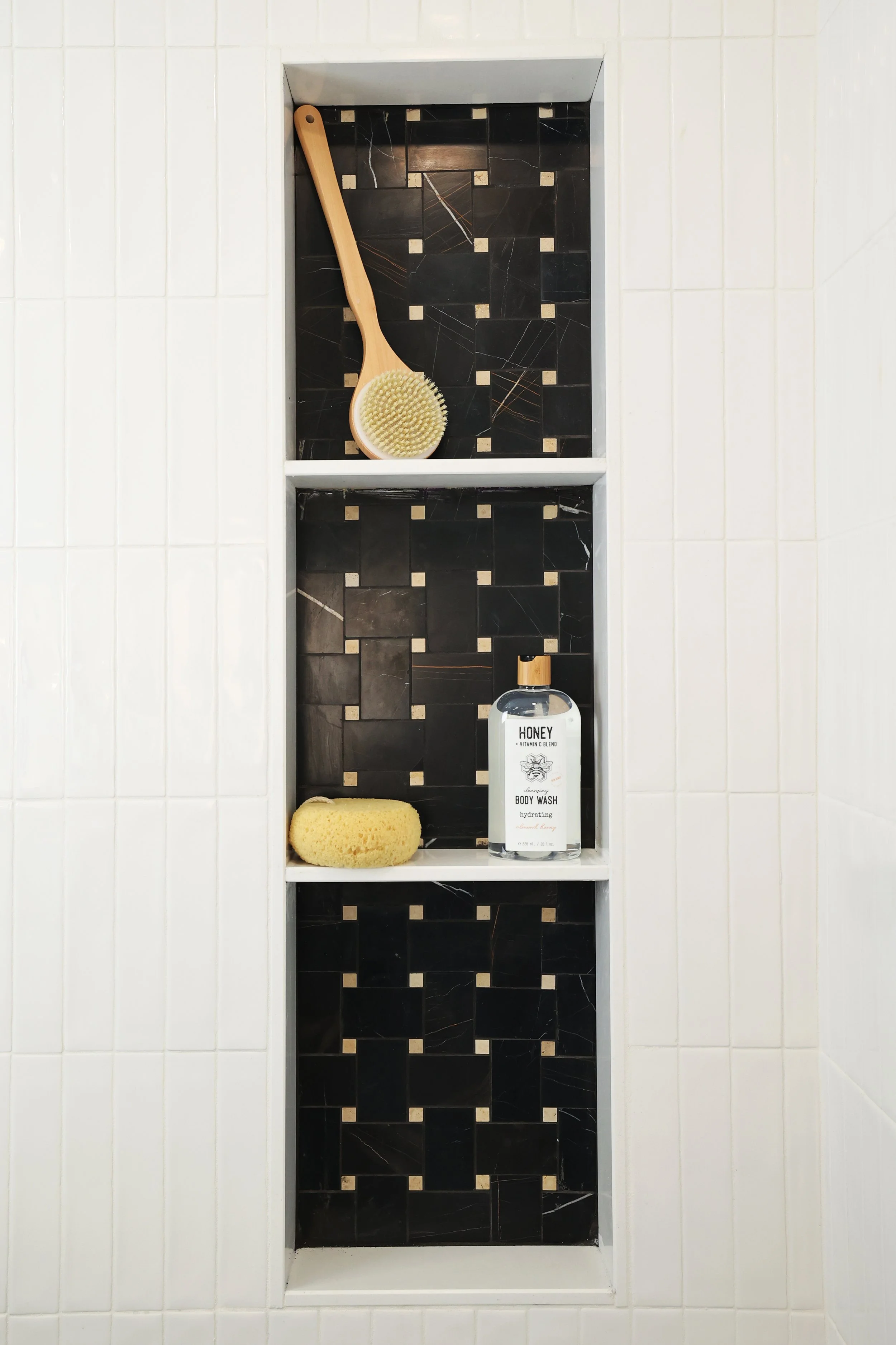 Built-in shower niche with black tile inset and brass accents in a Bethlehem NH bathroom.
