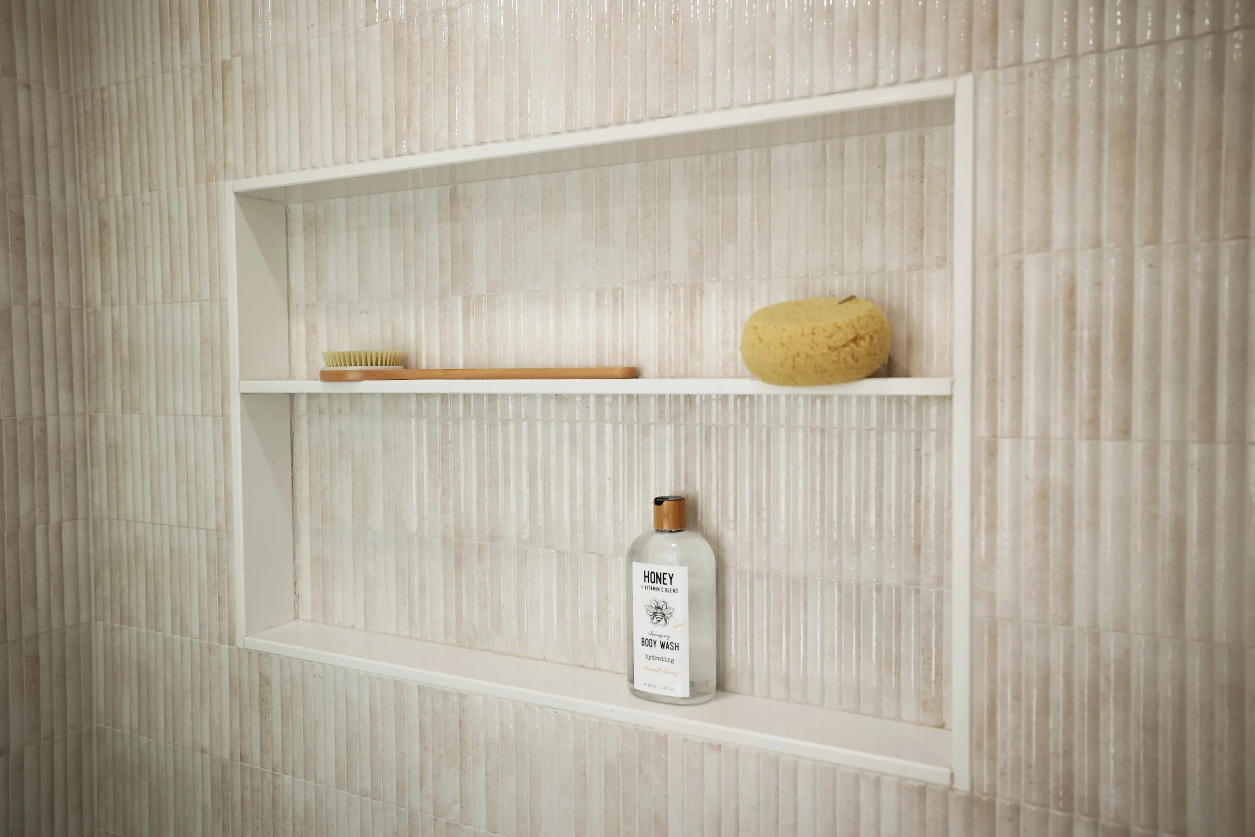 Built-in shower niche framed in fluted neutral tile within an organic modern bathroom design.
