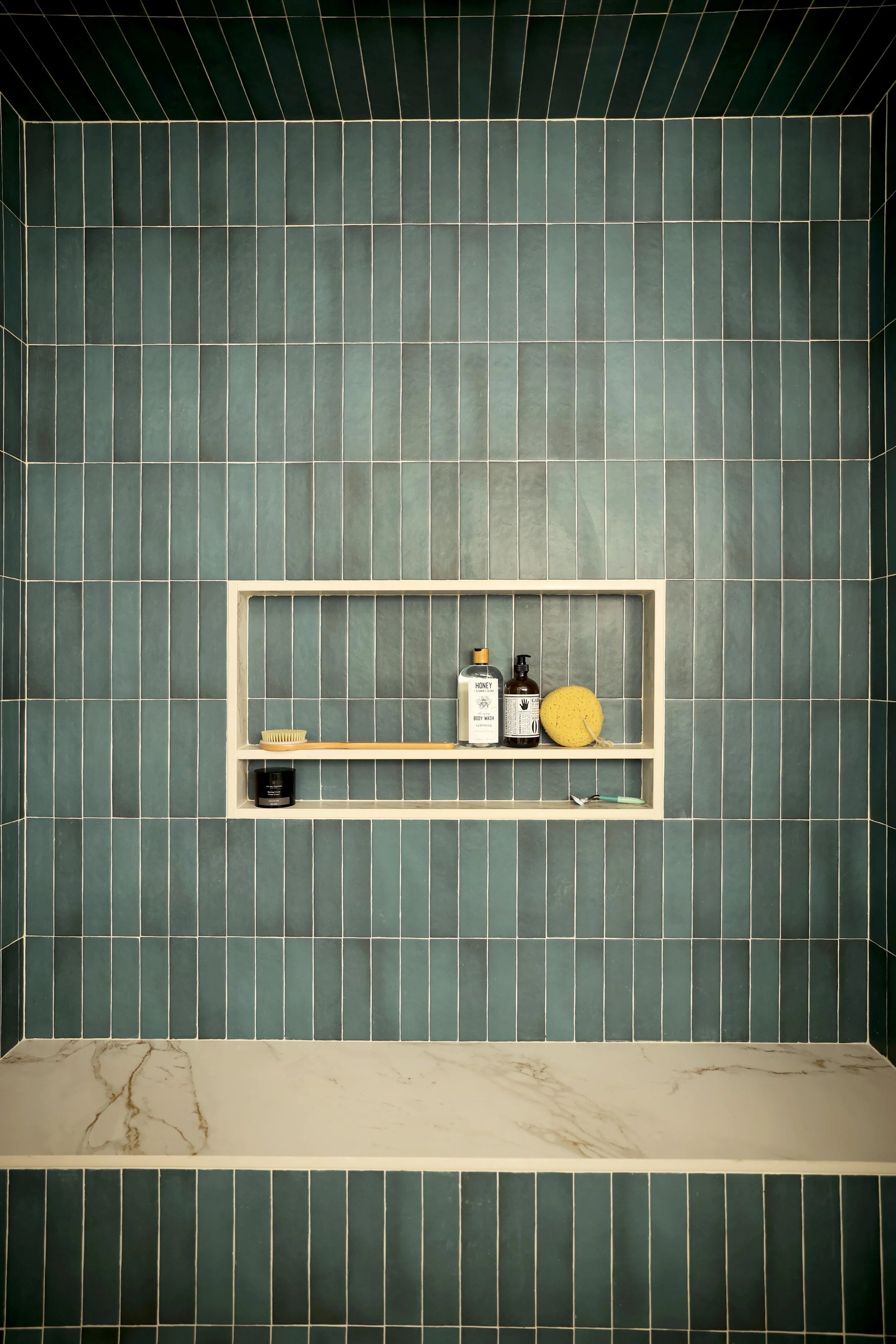 Built-in shower niche with blue vertical tile and marble shelf in Hanover NH primary bath