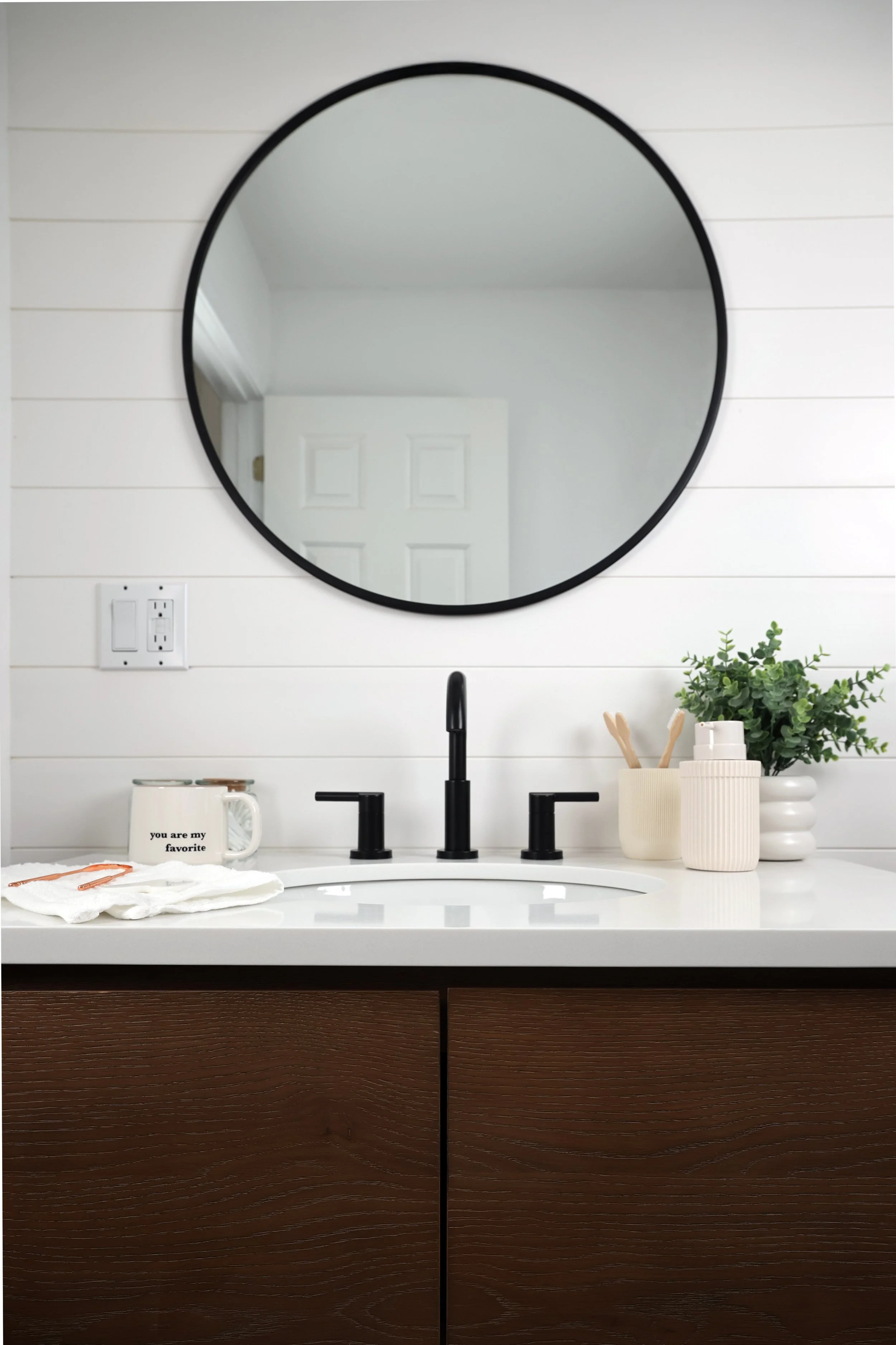 Bathroom vanity with matte black Kohler faucet and white shiplap wall in a Burke Vermont ski home.