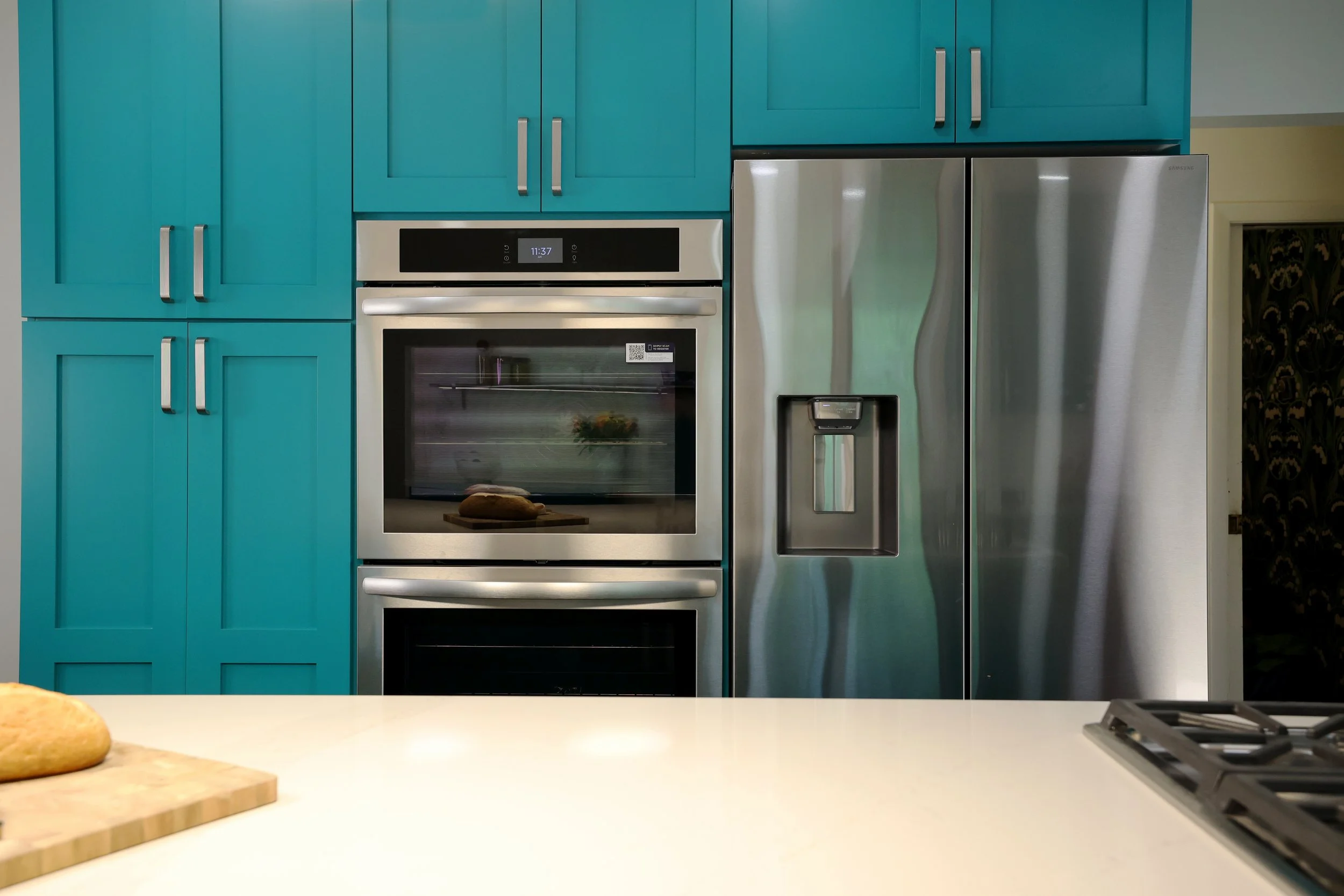 Kitchen appliance wall with teal cabinetry in a midcentury kitchen renovation in White River Junction Vermont.