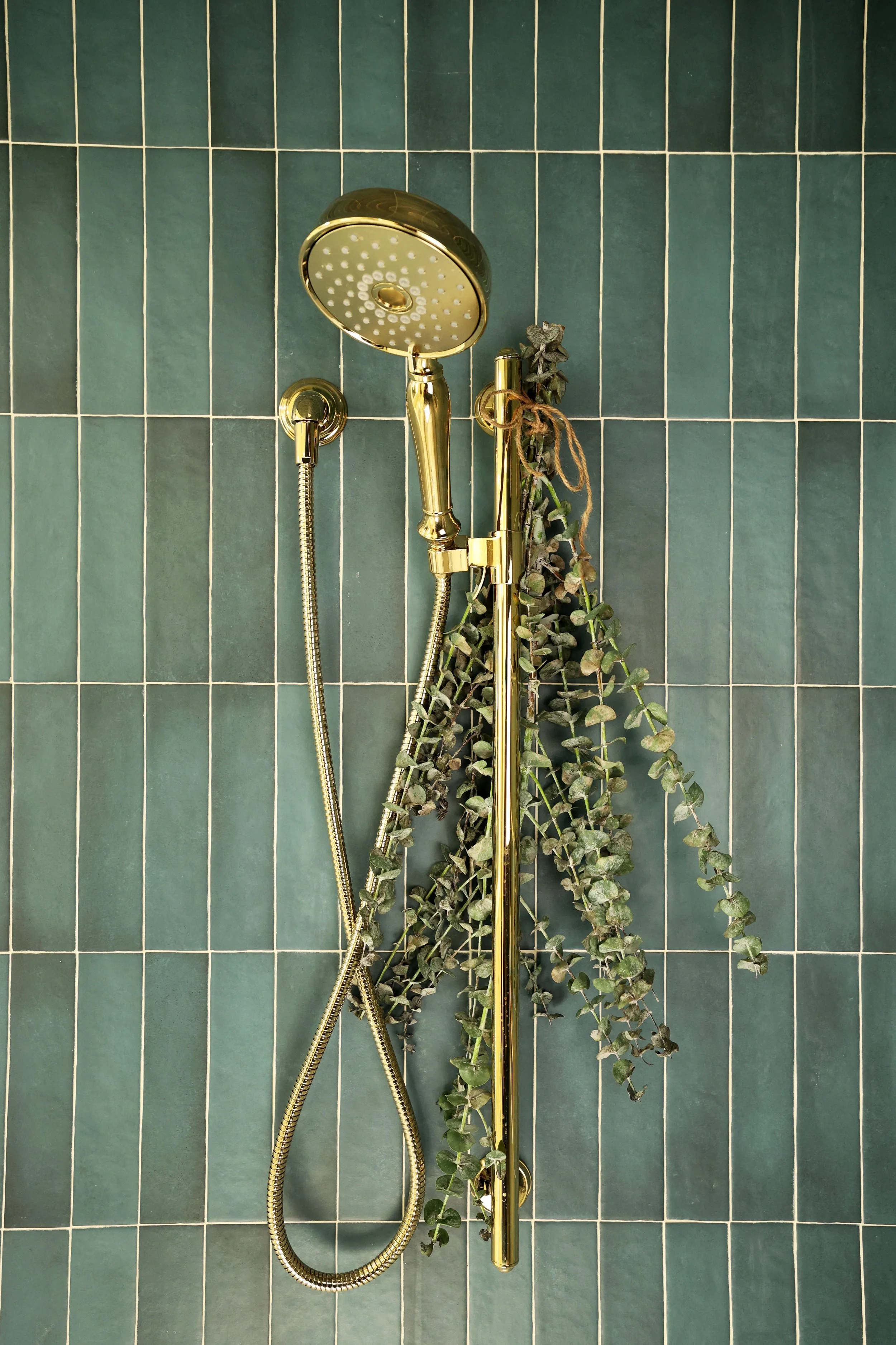 Polished brass shower fixture installed against deep blue vertical tile in Hanover NH primary bathroom renovation