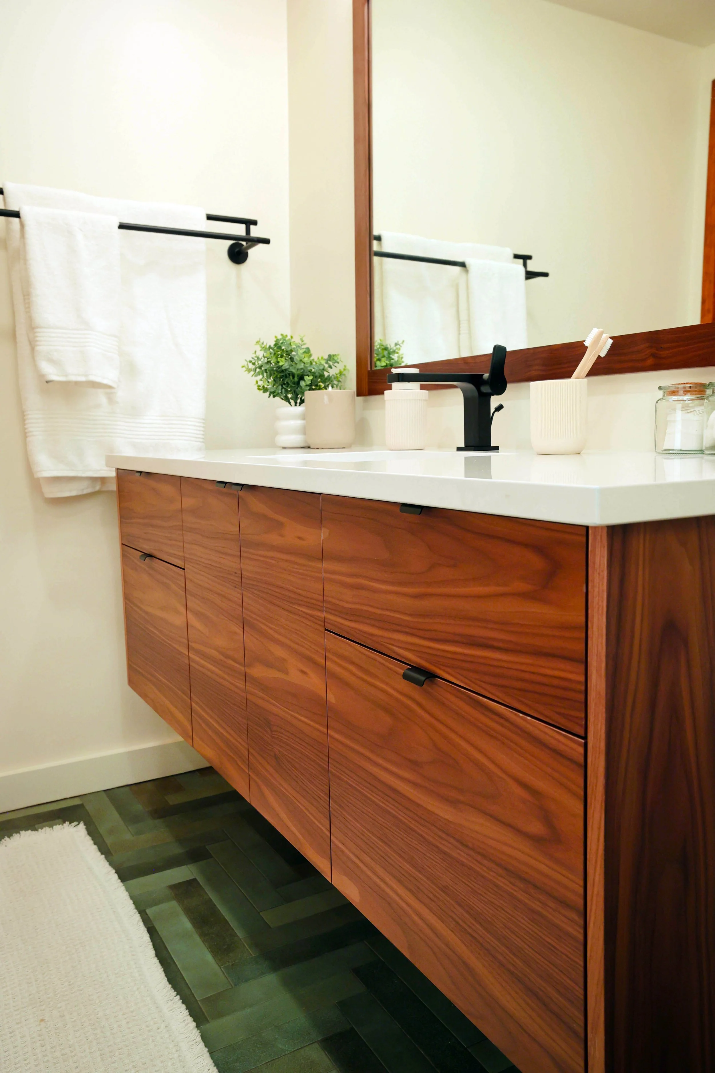 custom bathroom remodel in NH and VT with walnut floating vanity, black hardware, and white countertop.
