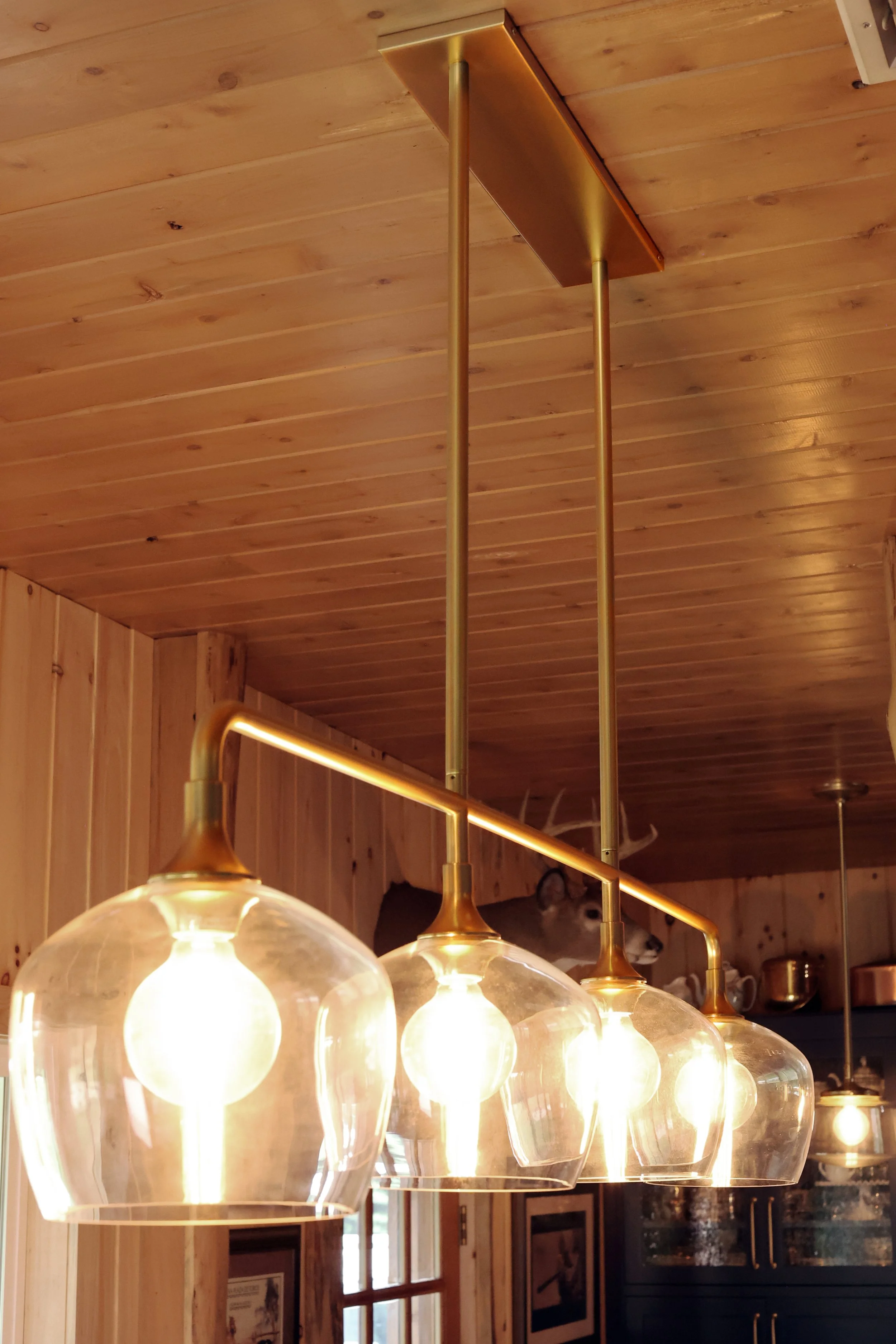 Rejuvenation pendant lighting above the island in a rustic New Hampshire lodge kitchen.