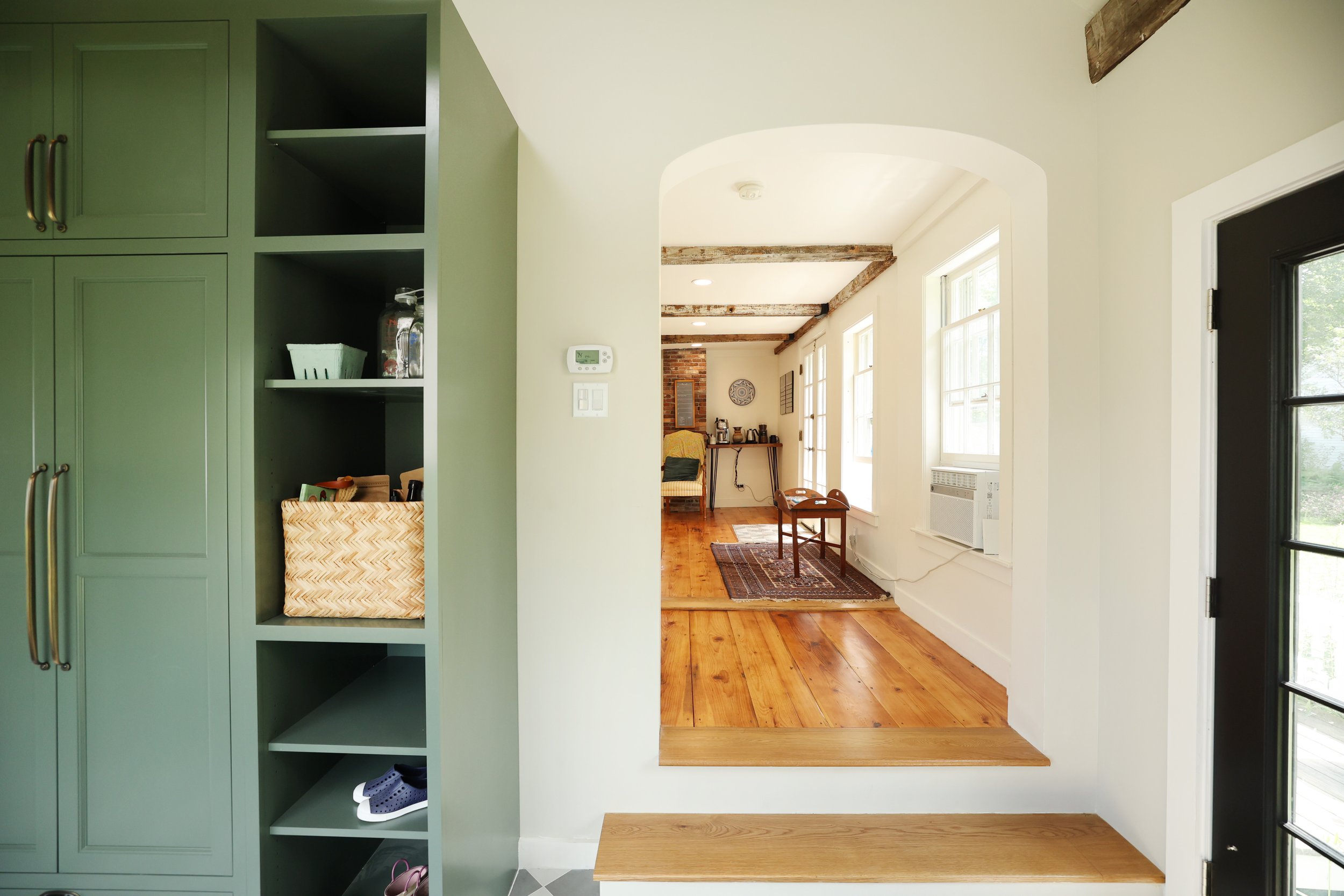 Arched opening connecting farmhouse mudroom to the main living area of a Vermont home.