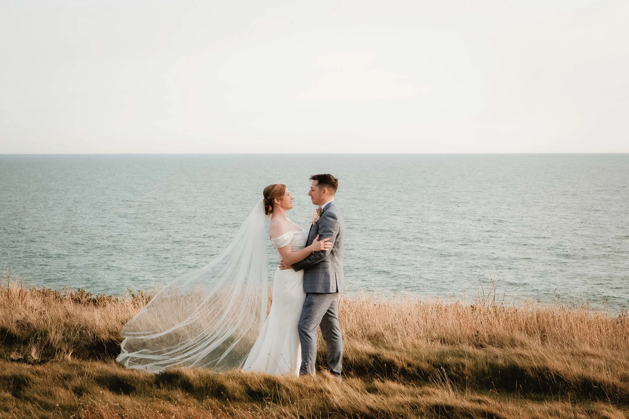 Romantic coastal wedding portrait with veil blowing in the wind, natural and elegant Isle of Wight wedding photography