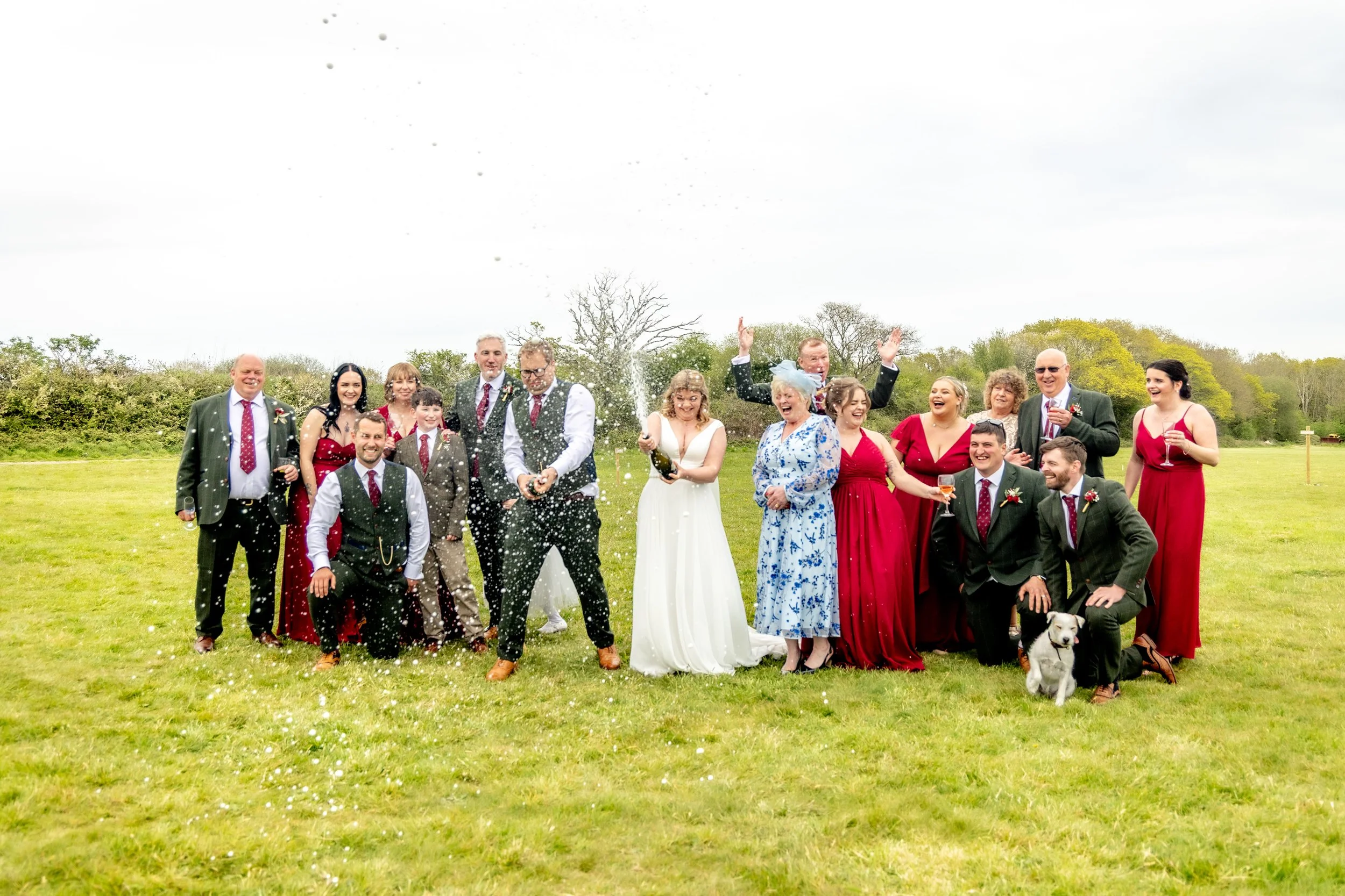 Wedding guests celebrating with champagne spray, candid group moment full of laughter and energy, relaxed wedding photography UK