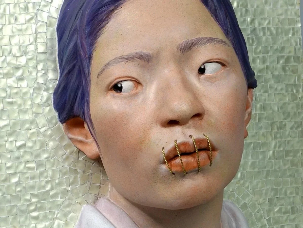 Nahaufnahme eines Künstlers mit lila Haar, der einen futuristischen Gesichtsausdruck zeigt, mit goldenen Klammern an den Lippen und einem mosaikartigen Hintergrund.