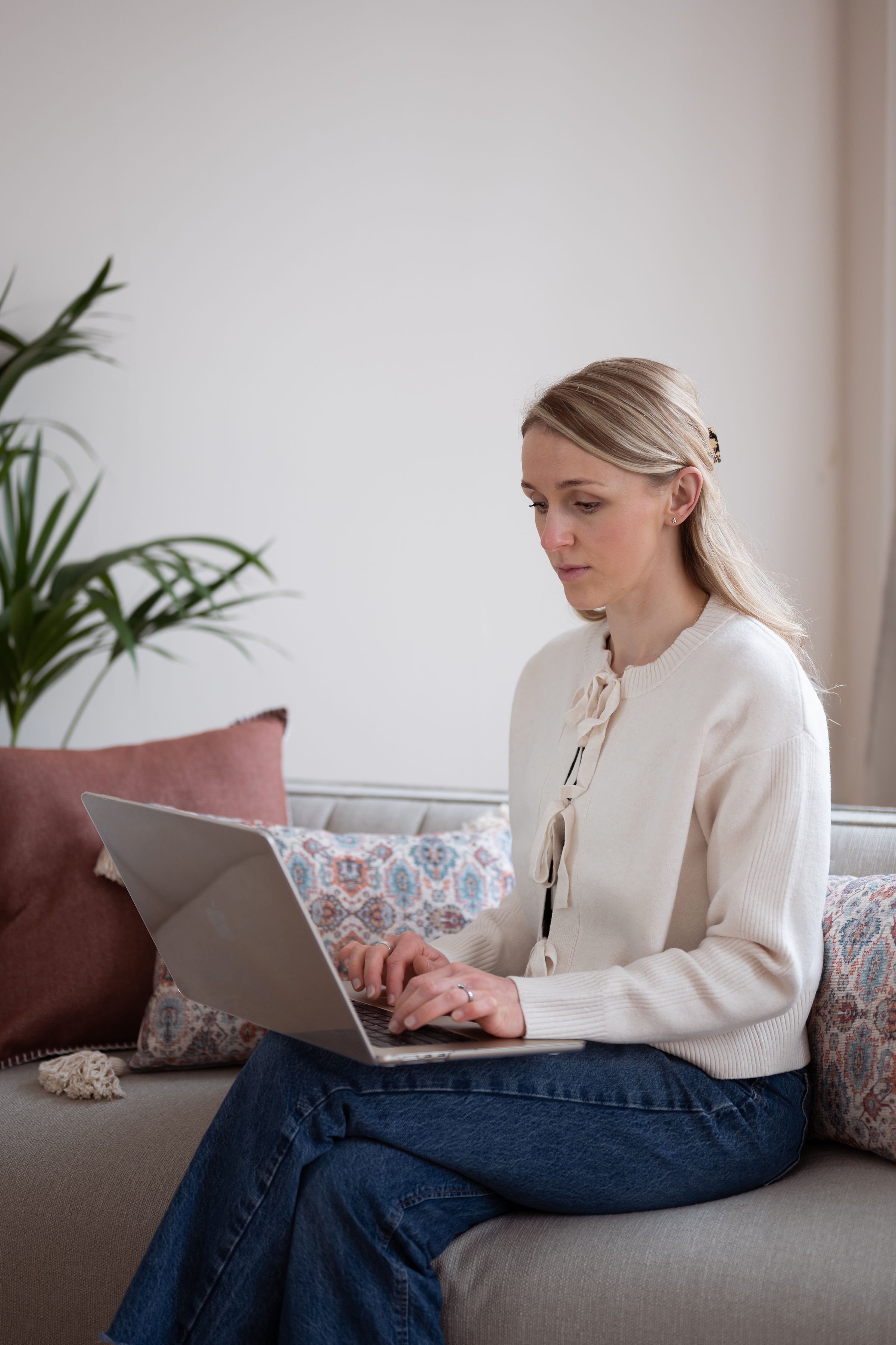 Mel sits on sofa working on laptop