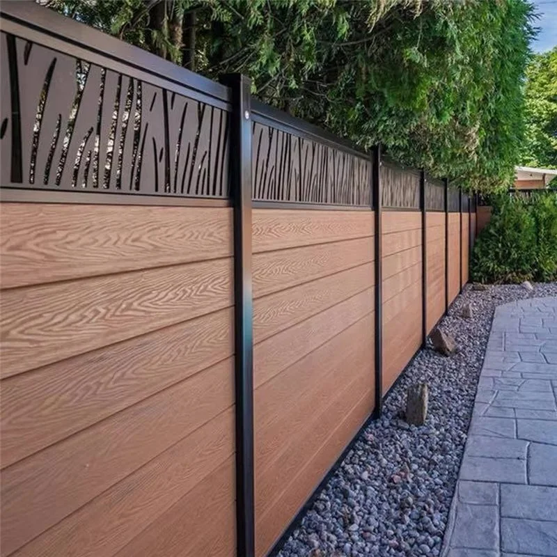 Wooden and metal privacy fence along a walkway with rocks and trees.