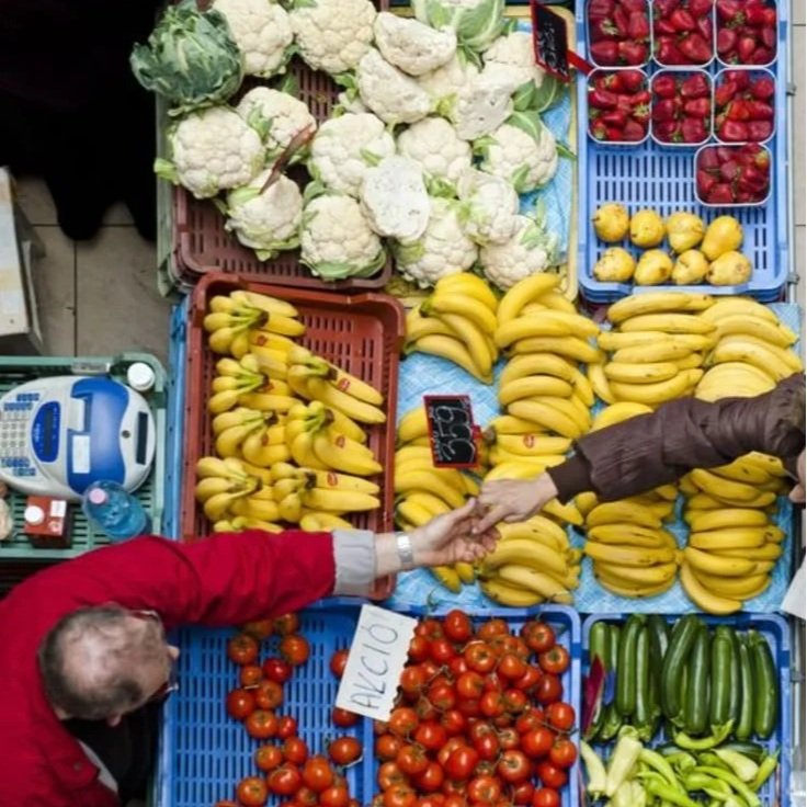A vibrant open-air market bursting with fresh produce and everyday Italian life.