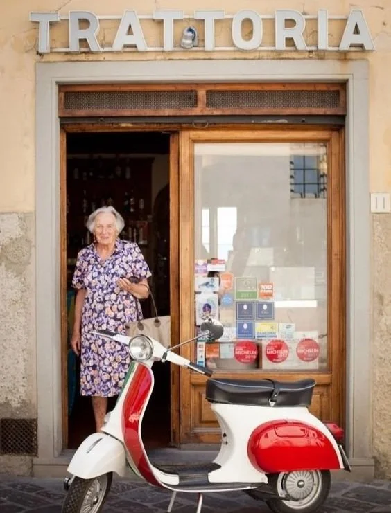 A timeless Italian trattoria entrance with a classic scooter and local character.