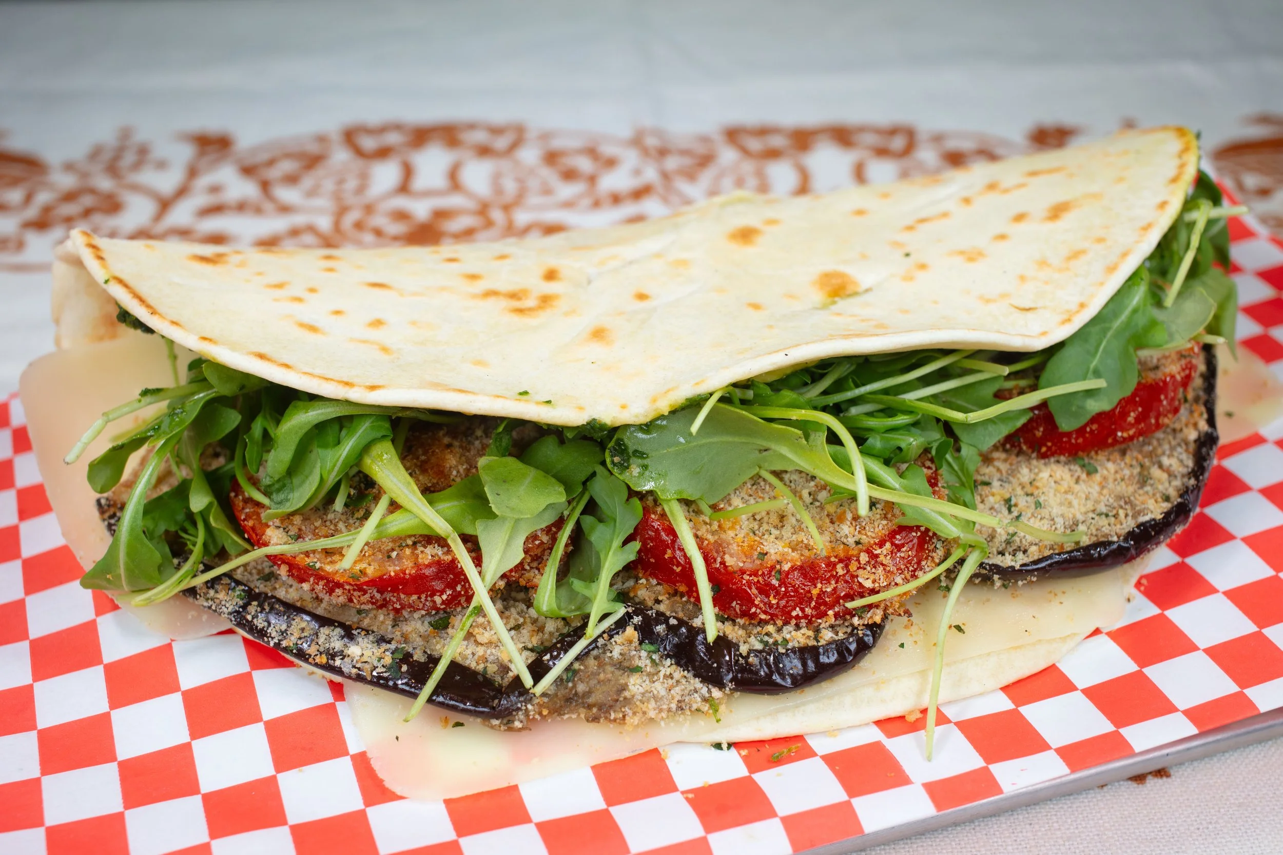 Piadina filled with Roasted Eggplants and Tomato, Breadcrumbs, Fontina cheese, Arugula, Parsley caper pesto