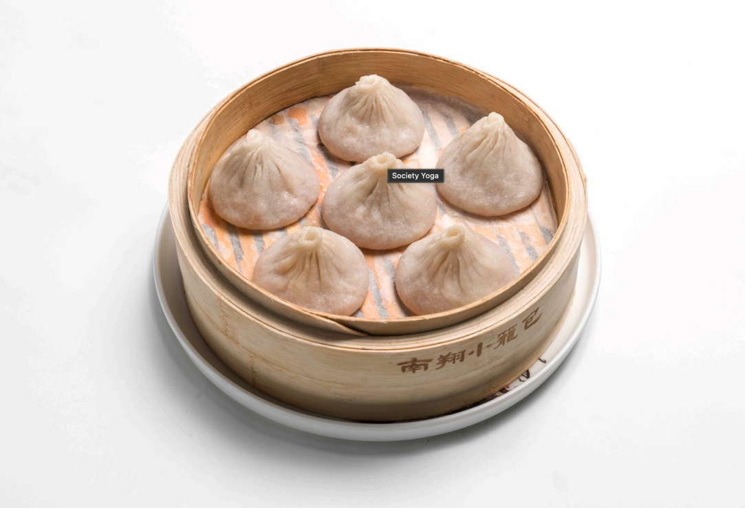 Steamed dumplings in a bamboo steamer on a white plate