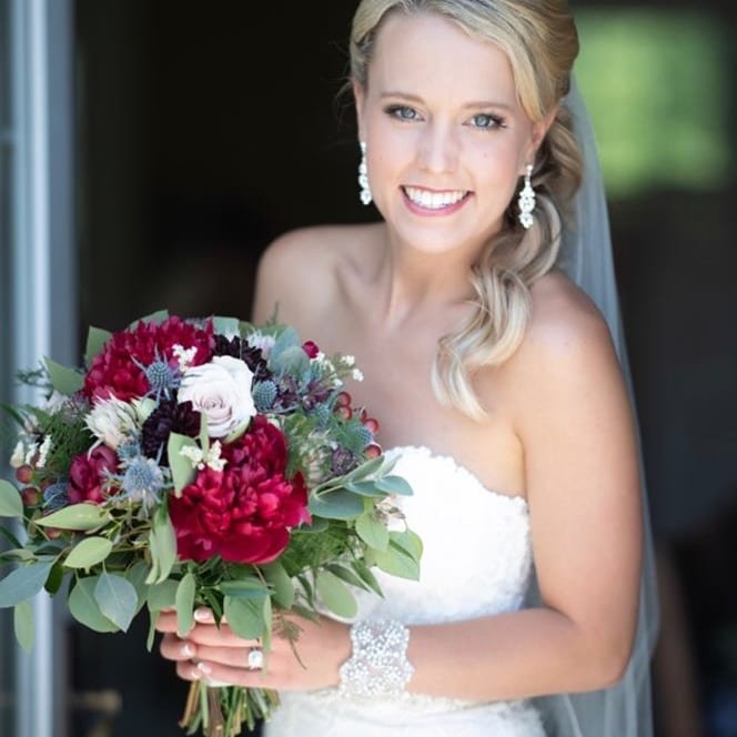 Bride with blonde hair in a strapless white wedding dress holding a large bouquet – styled by One Salon & Bridal Co in St. Charles, IL
