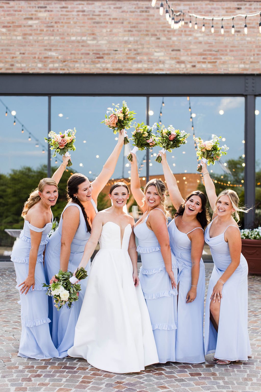 Group of bridesmaids and bride celebrating with bouquets outdoors during a wedding – bridal party prep at One Salon & Bridal Co in St. Charles, IL