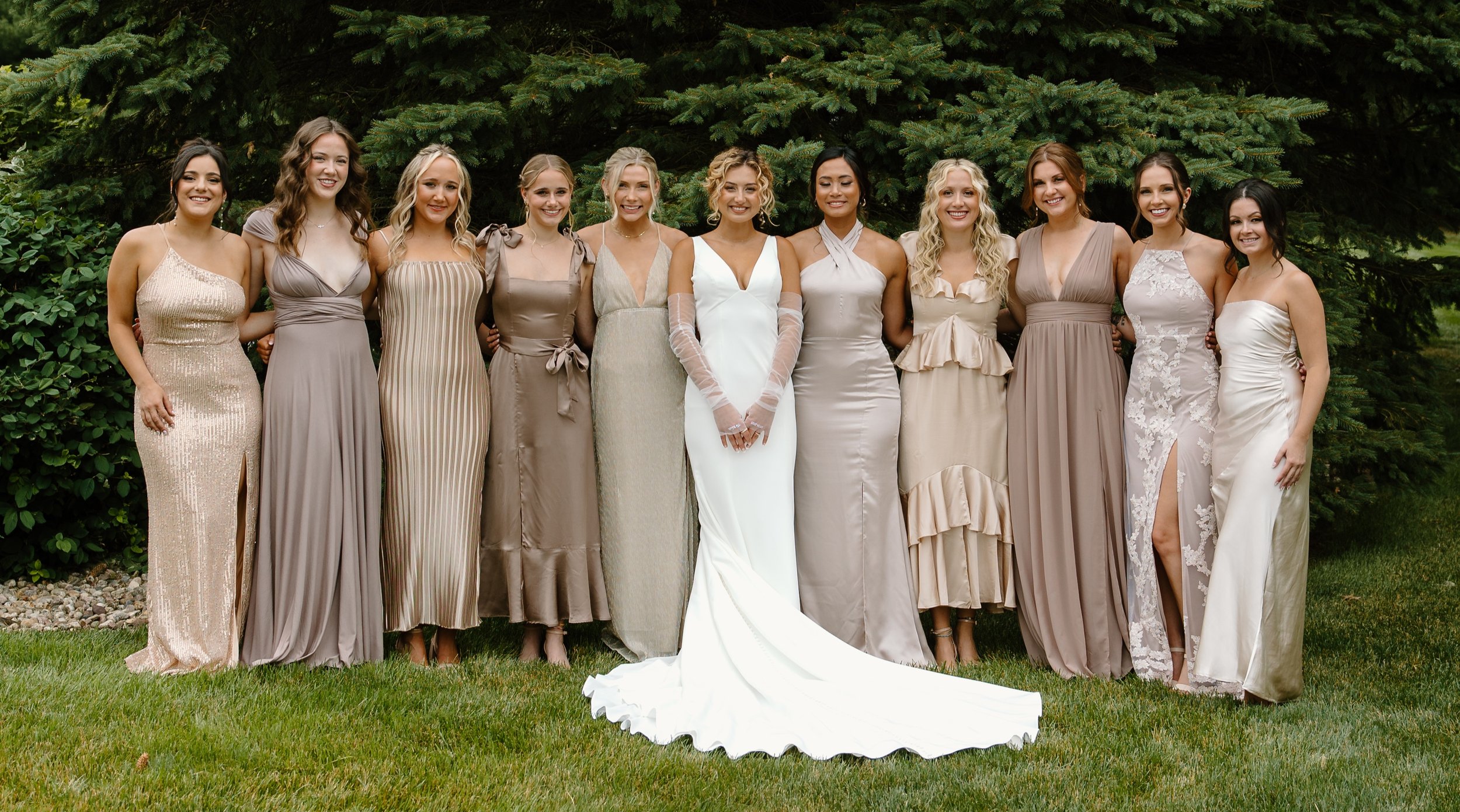A bride in a white wedding gown standing among her bridesmaids – styled by One Salon & Bridal Co in St. Charles, IL