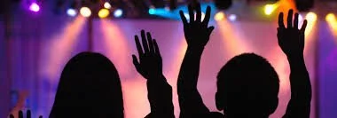 House on grassy hill with snow-capped mountains in background