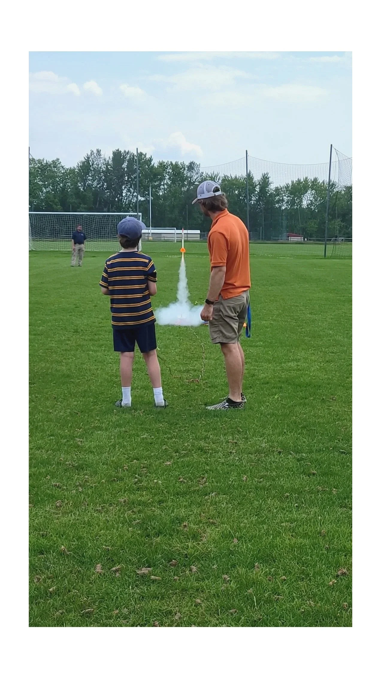 Camper and staff member launching rocket in large open field