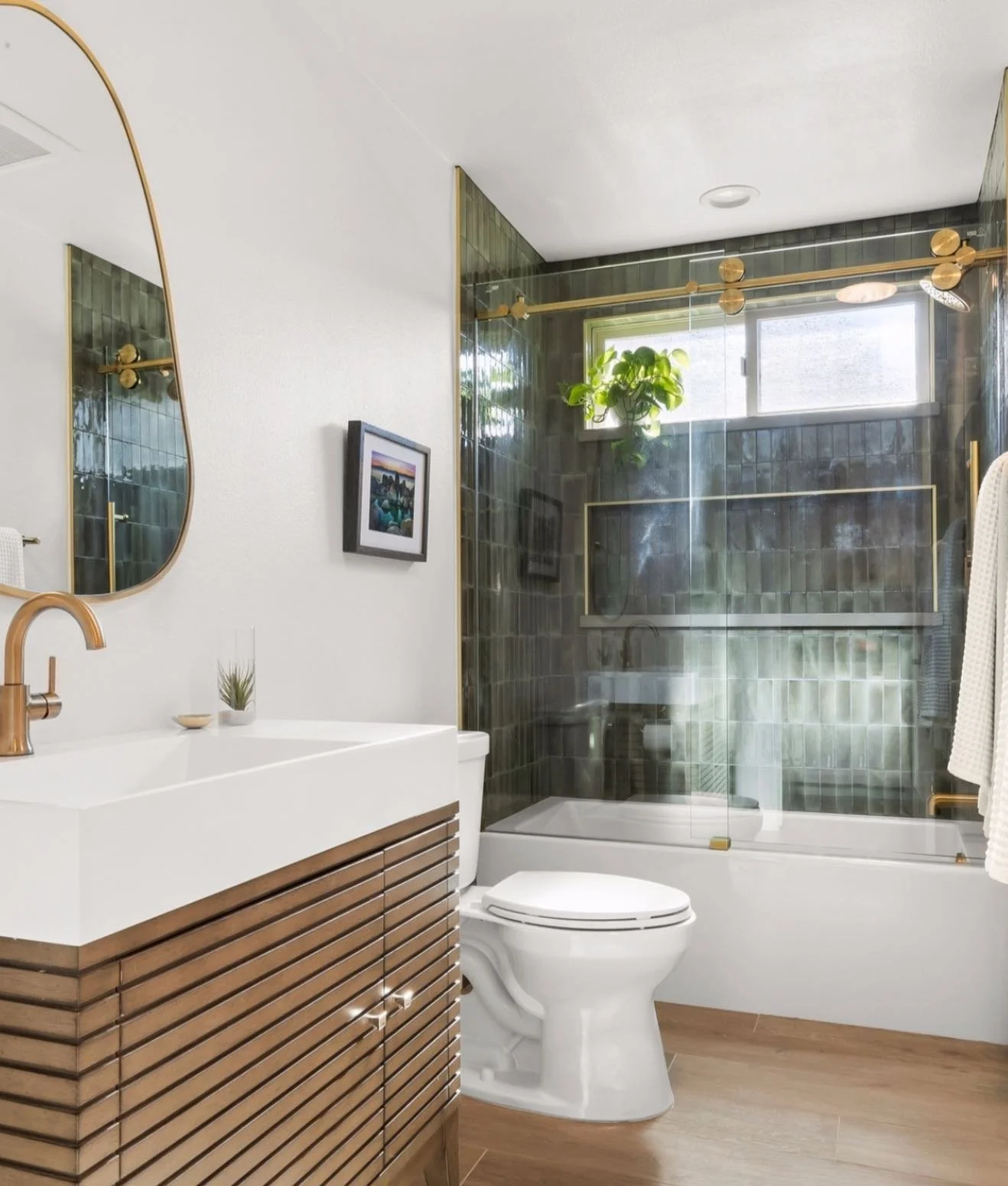 Fresh, modern, and full of warmth. This bathroom remodel pairs rich green tile with brass accents and natural wood for a clean, spa-like feel ✨