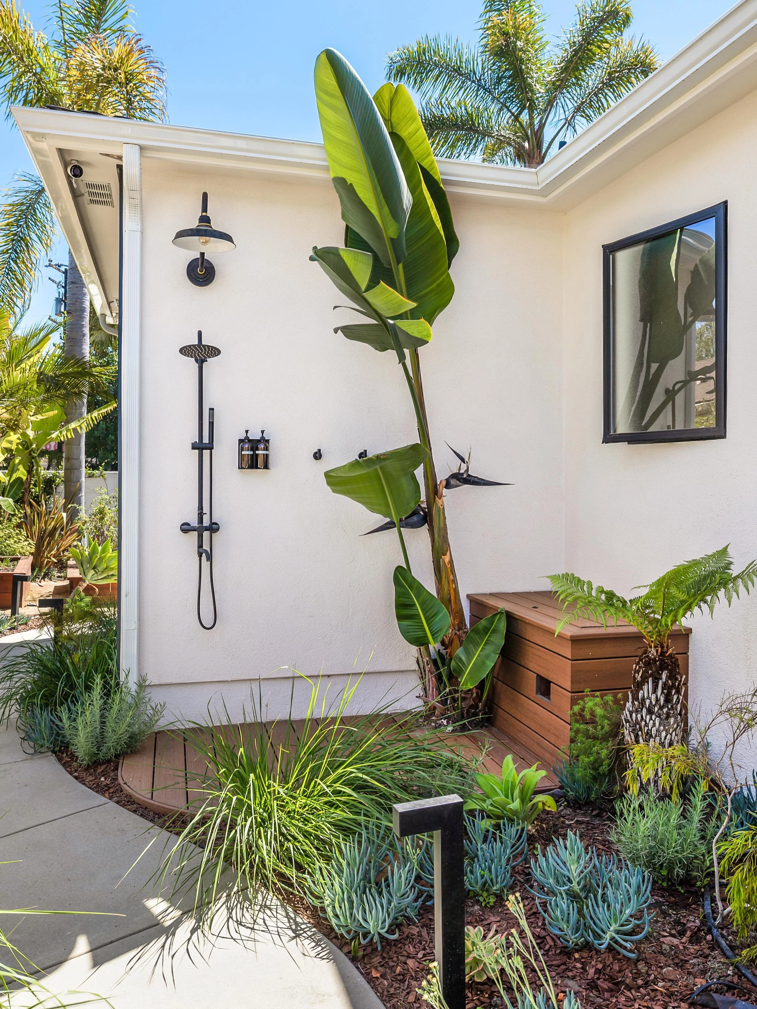 Spa-inspired outdoor shower with tropical landscaping and custom wood detailing ✨